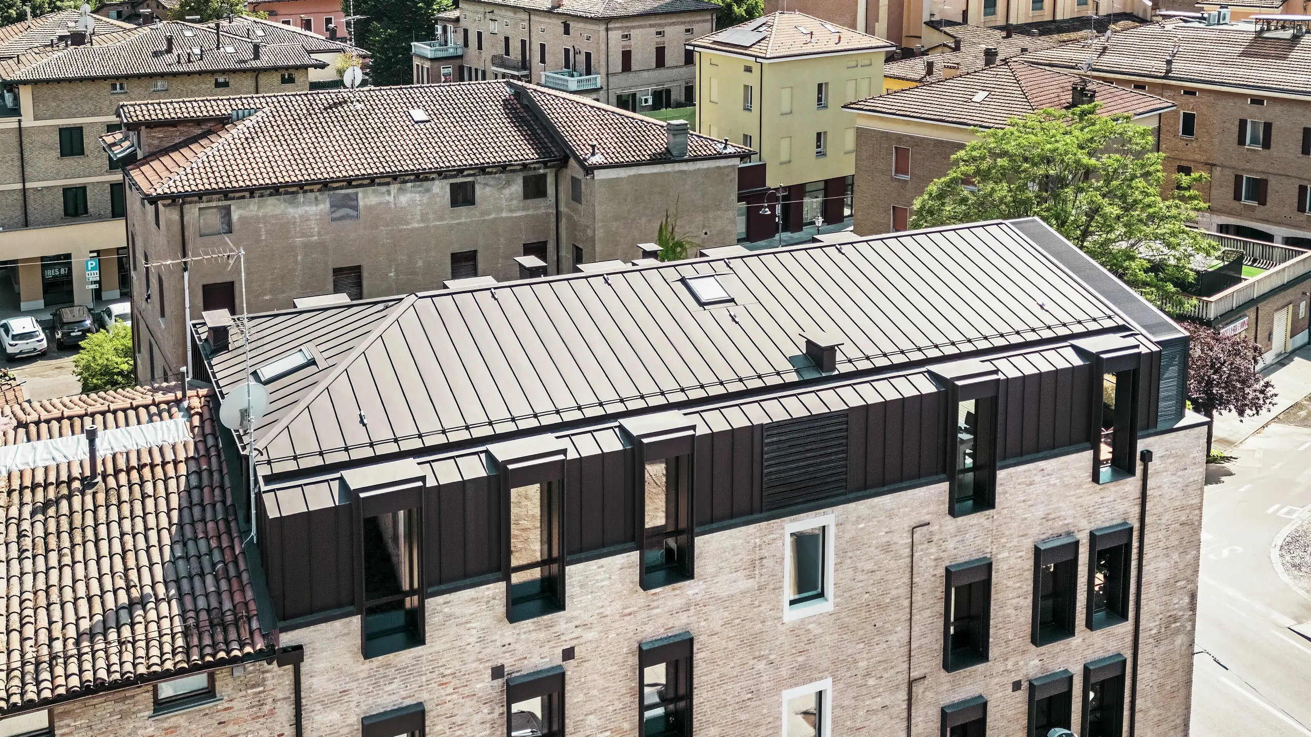 Modernisiertes Backsteinhaus in Italien mit PREFALZ Aluminiumdach in der Farbe P.10 Nussbraun – ästhetische Verbindung von traditioneller Ziegelarchitektur und moderner, langlebiger Dachlösung