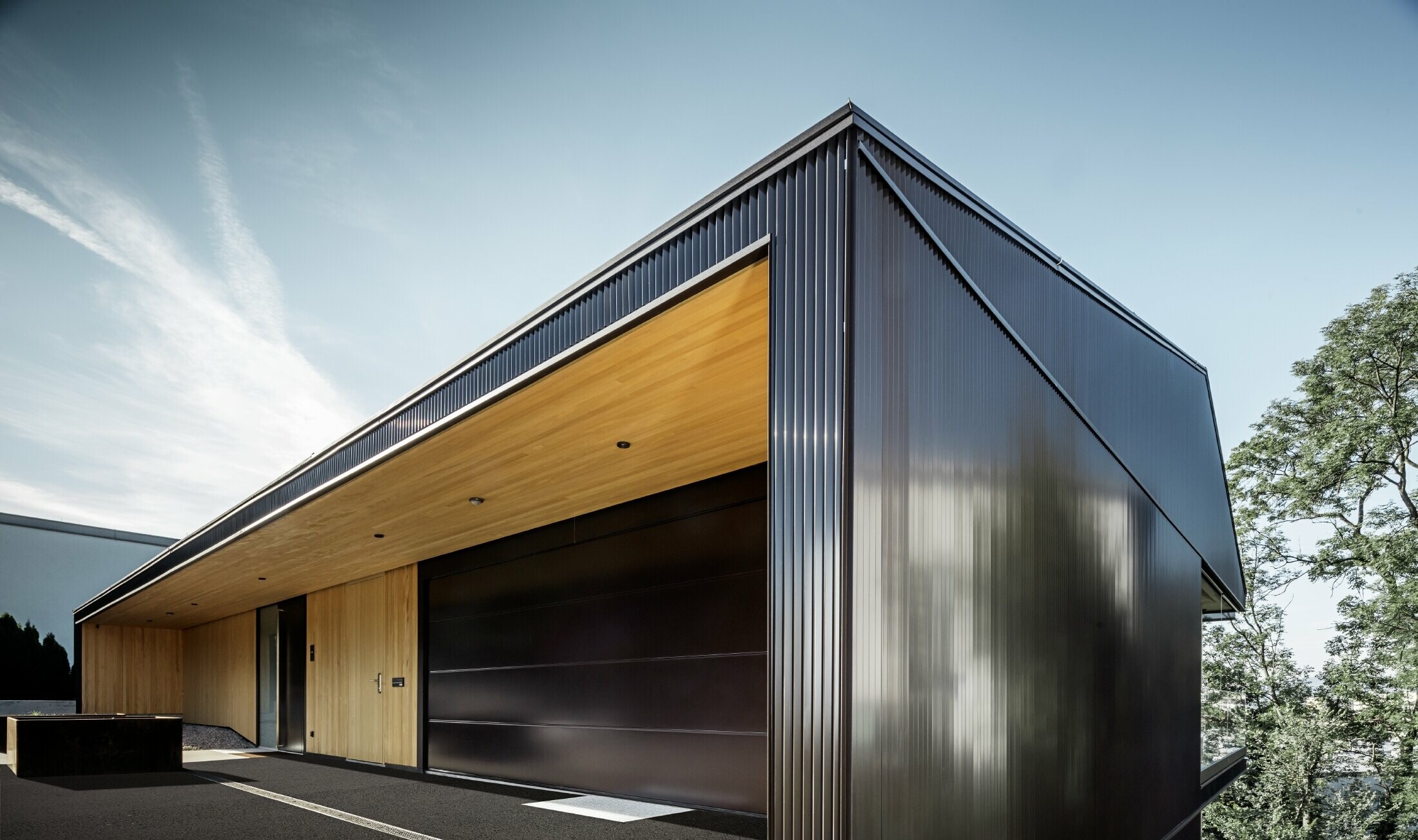 Accesso per garage di una casa unifamiliare, la facciata è rivestita con il profilo a zeta PREFA in marrone scuro. 