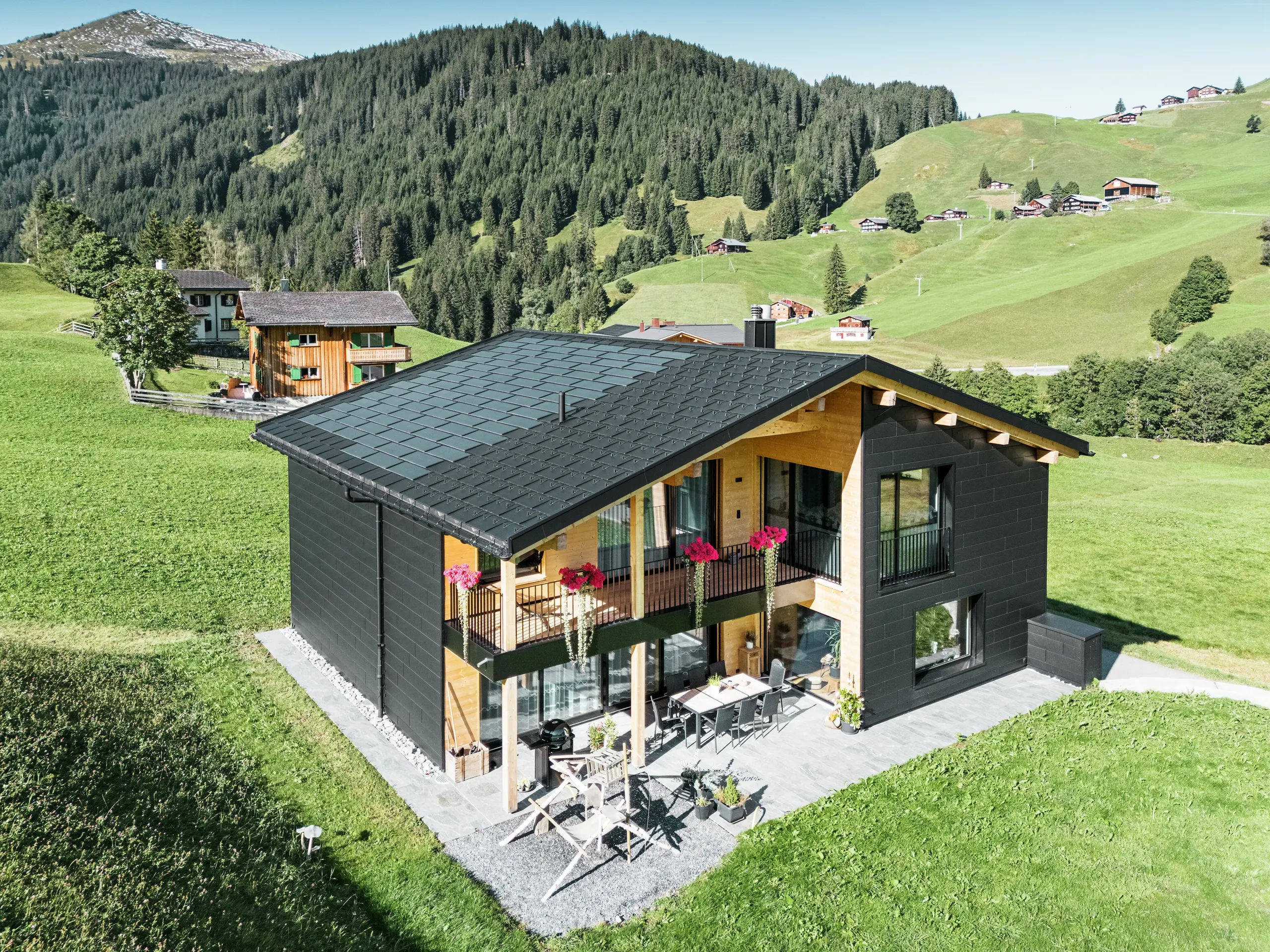 L'elegante casa unifamiliare nella zona collinare di Ascharina (Svizzera) mostra come l'alluminio e il legno possano essere perfettamente combinati.I robuste doghe per facciate PREFA Siding.X in P.10 nero si armonizzano con il tetto in tegole fotovoltaiche PREFA e tegole R.16 dello stesso colore. La pelle in alluminio di lunga durata protegge l'edificio in modo affidabile dalle sfide del clima alpino.