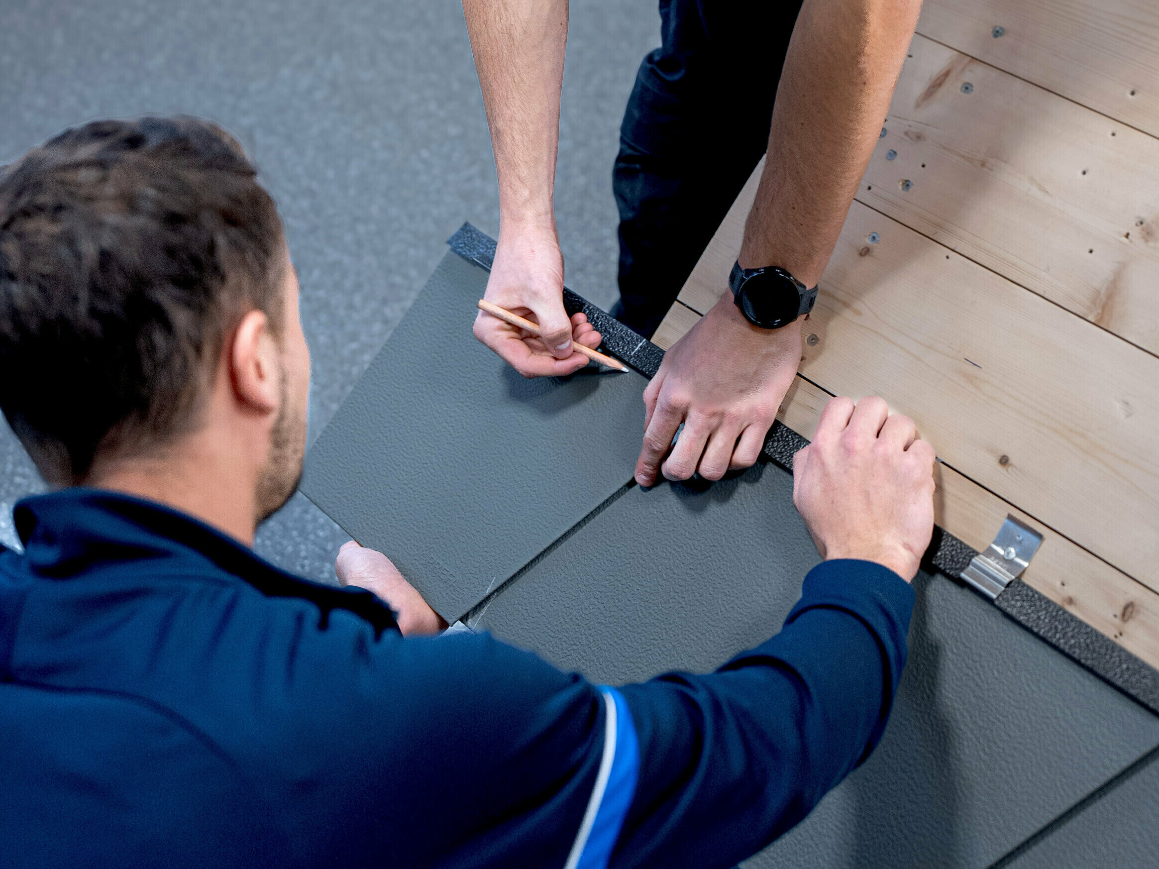 PREFA Lehrverleger zeigt in der PREFA Academy einem Teilnehmer die richtige Verlegung der PREFA Produkte.