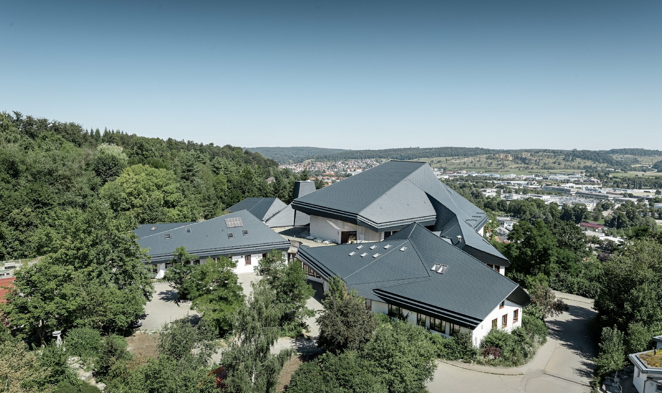 Waldorfschule in Heidenheim mit neu saniertem Dach, die große Dachfläche mit vielen Verwinkelungen und Dachneigungen wurde mit der PREFA Dachschindel in anthrazit eingedeckt