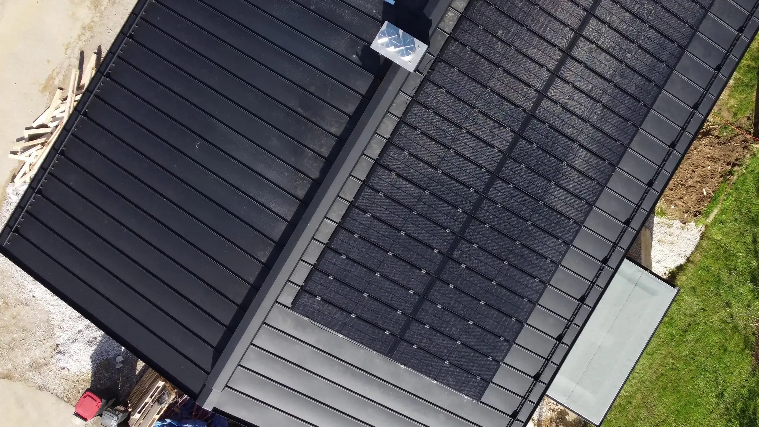Vista dall'alto di un tetto PREFALZ con moduli solari montati, che mostra l'integrazione di moduli fotovoltaici vetro/vetro e superfici del tetto scoperte.
