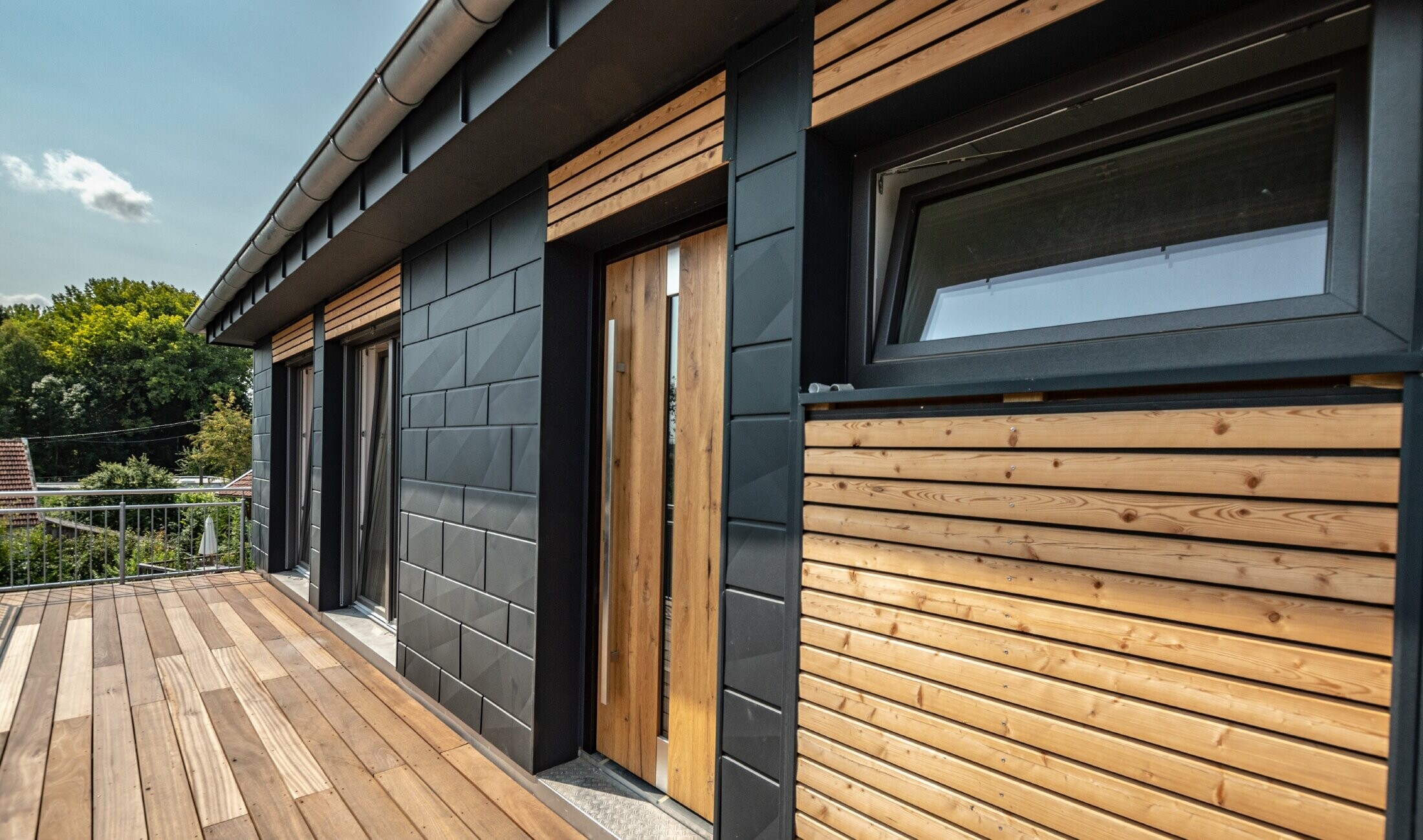 Design della facciata con combinazione di materiali alluminio - PREFA doga.X in antracite - e modanature orizzontali in legno.