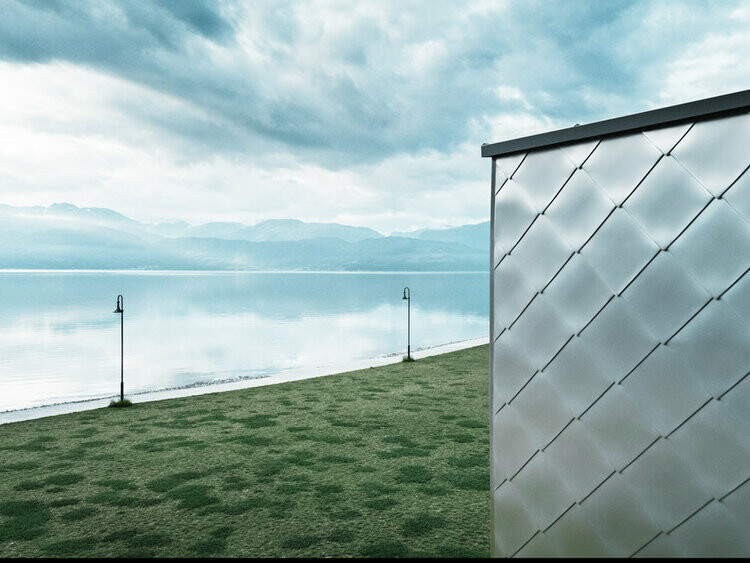 L'immagine mostra un primo piano di un edificio polifunzionale, l'ardangerbadet Healthcare Center. Rivestito in Scaglia 44 x 44 alluminio naturale. I fiordi del Hardangerfjord si vedono sullo sfondo.