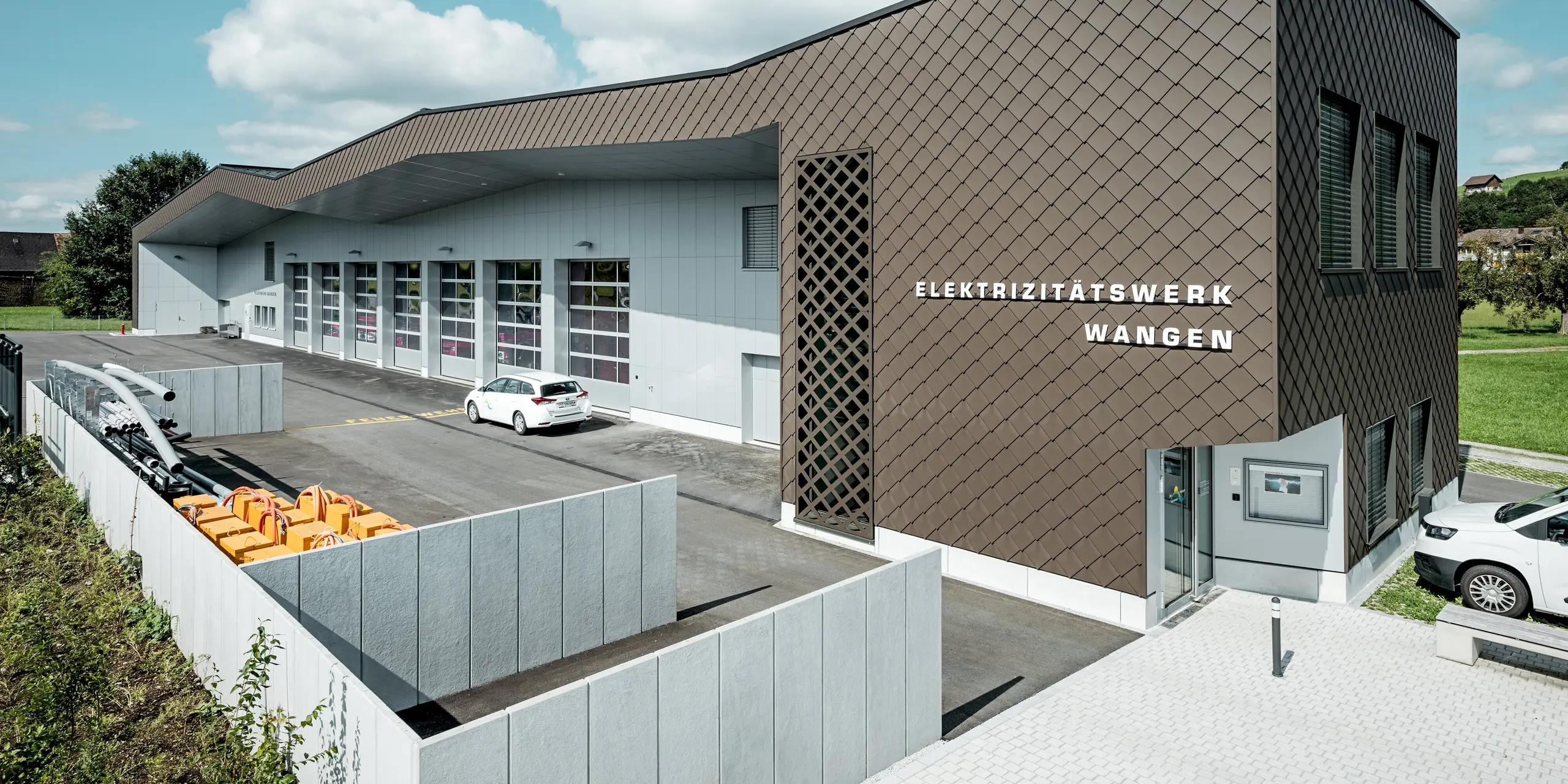 Modernes Feuerwehr- und Elektrizitätswerk in Wangen, Schweiz, mit markanter Gebäudehülle aus PREFA Wandrauten 29 × 29 in P.10 Braun. Die dynamische Rautenstruktur verleiht der Fassade Tiefe und eine unverwechselbare Optik. Aluminium Verbundplatten in P.10 Prefaweiß setzen helle Akzente. Die langlebigen PREFA Aluminiumprodukte überzeugen durch hohe Witterungsbeständigkeit, geringen Wartungsaufwand und maximale Gestaltungsfreiheit.