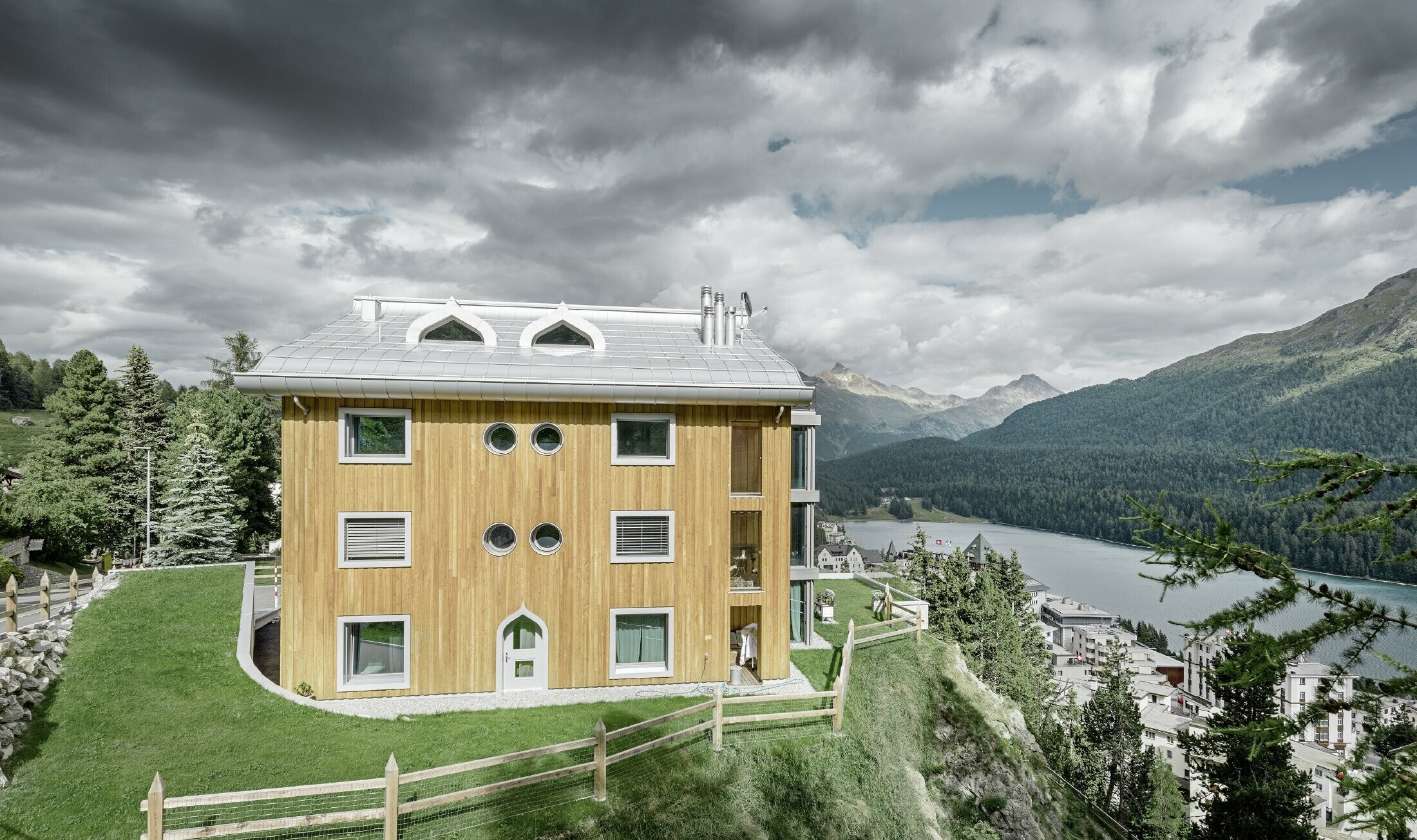 Complesso residenziale a St. Moritz con facciata in legno e copertura in alluminio con grondaia curva in silver metallizzato