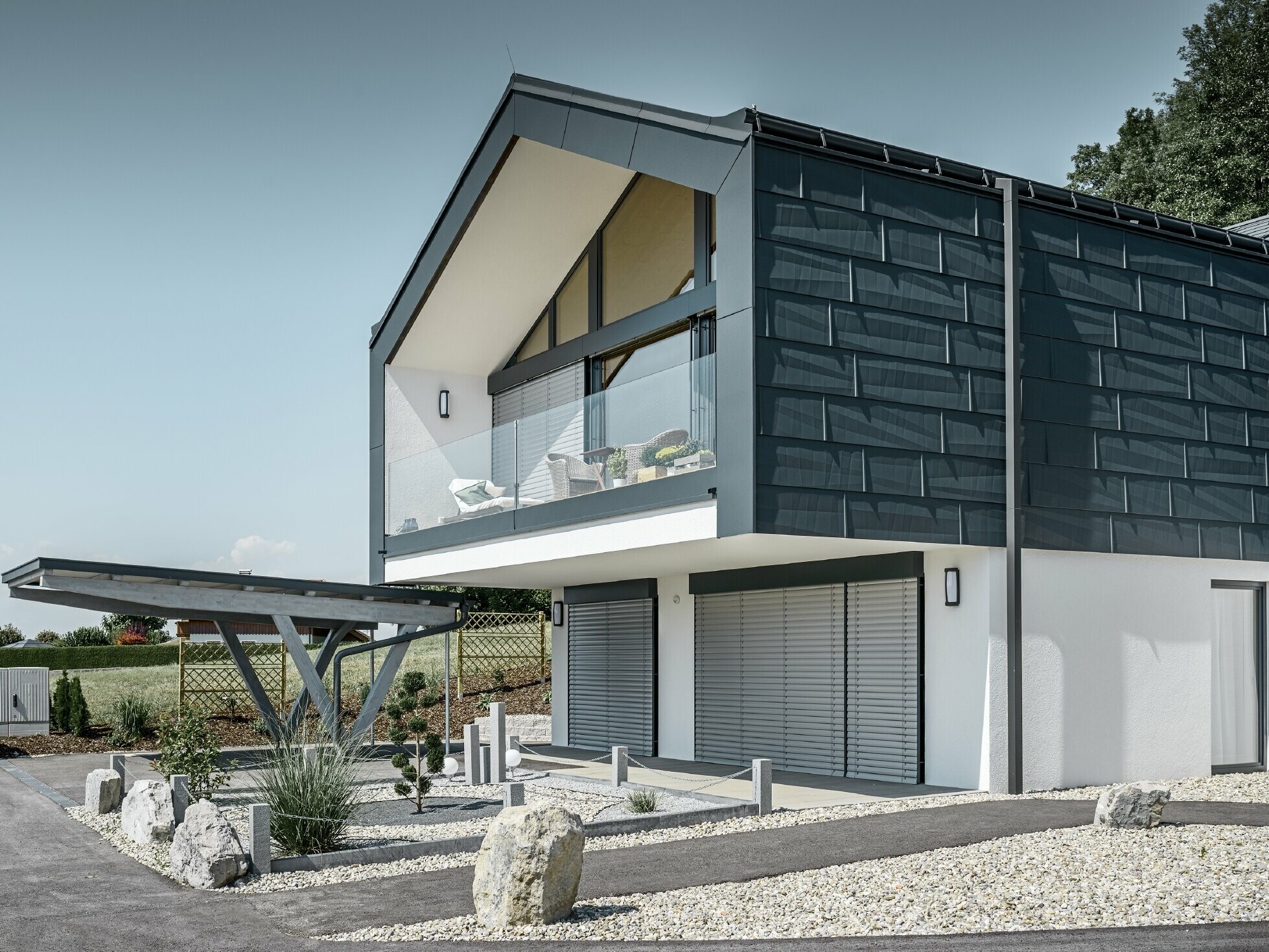 Casa plurifamiliare moderna con una facciata in vetro, copertura e facciata sono stati rivestiti con il pannello per coperture e facciate FX.12 di PREFA in antracite