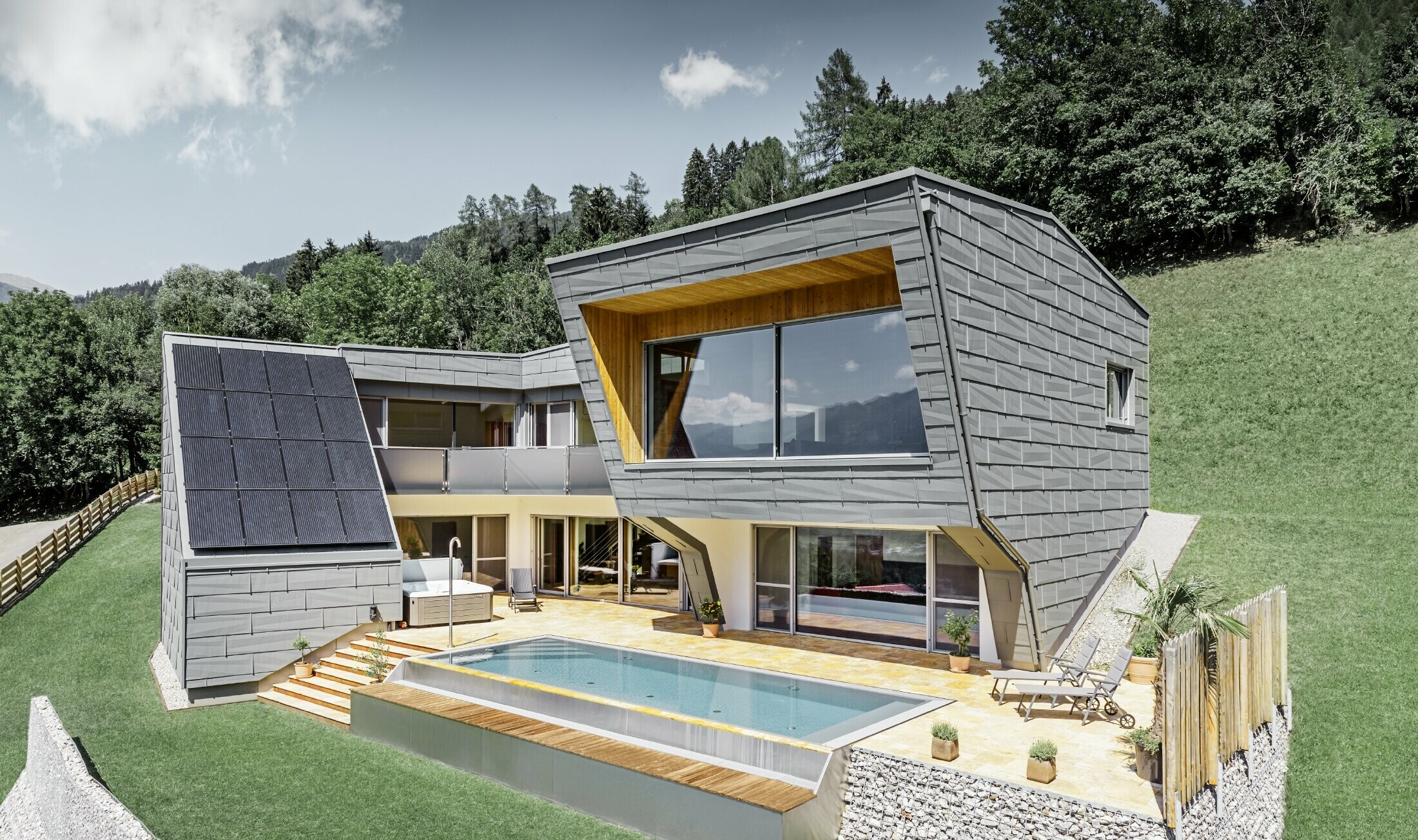 La moderna casa unifamiliare in pendenza con piscina è stata rivestita con il pannello per facciata FX.12 di PREFA in P.10 grigio chiaro.