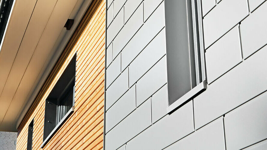 Combinazione di alluminio - doghe PREFA in grigio alluminio - con una facciata in legno. Posa orizzontale, fughe sfalsate.