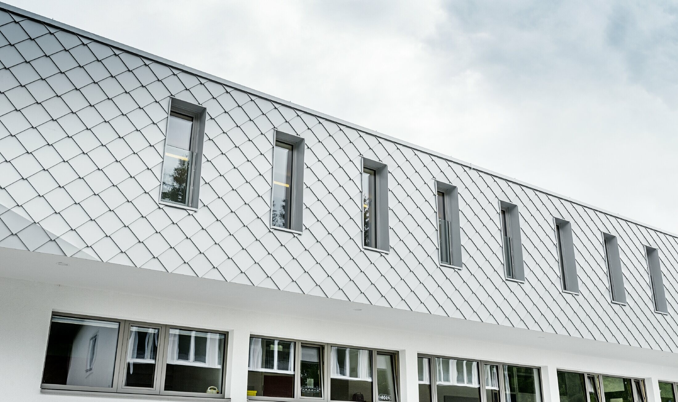 Neu gebauter Kindergarten in Kaprun mit einer modernen Aluminium Fassade mit der PREFA Wandraute in prefaweiss