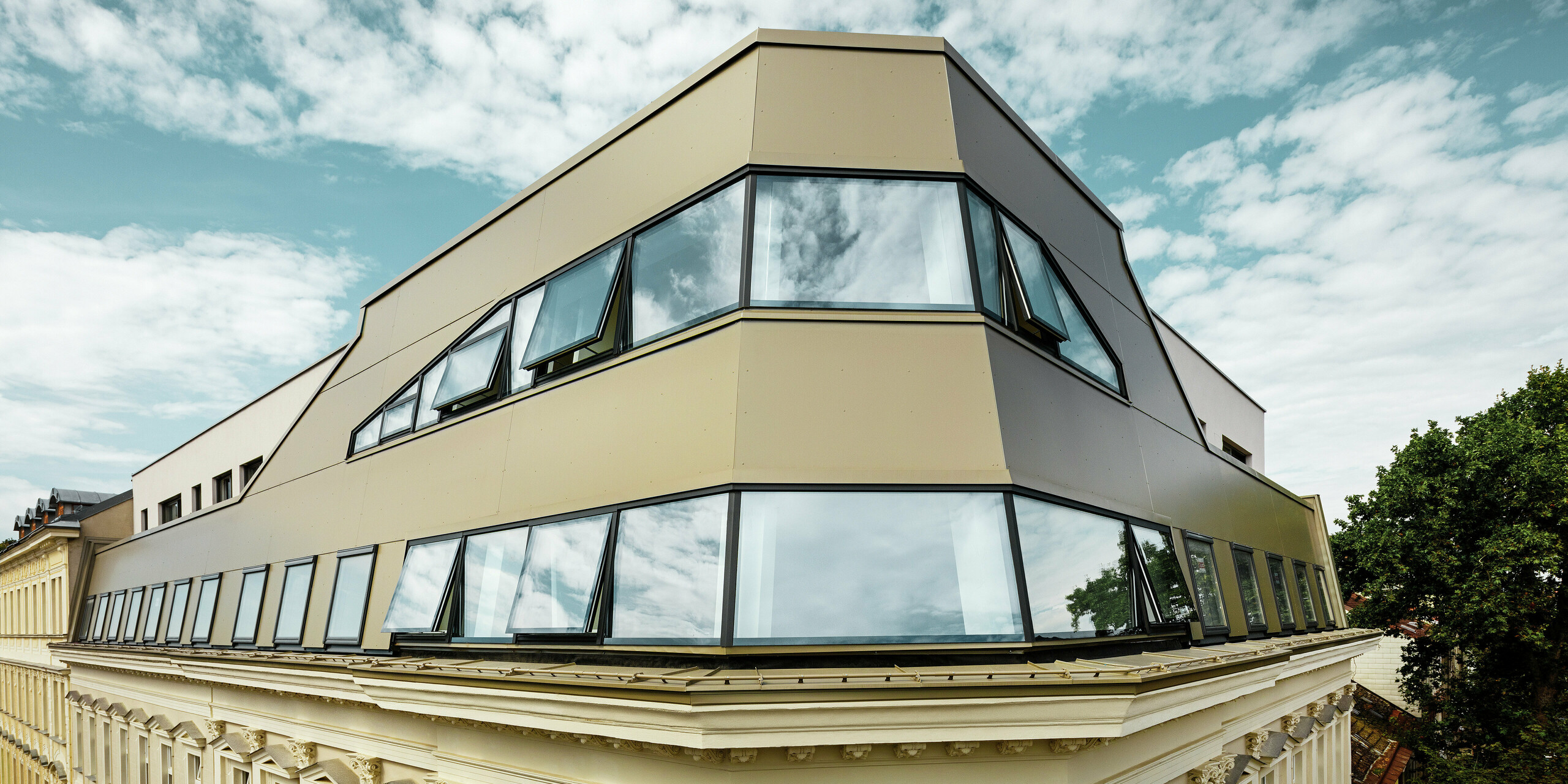 Die markante Dachkante des sanierten Gründerzeithauses in der Schloßhofer Straße in Wien zeigt den gelungenen Einsatz von PREFA Aluminium Verbundplatten in Bronze. Die Fassadengestaltung verbindet moderne Architektur mit dem klassischen Stil des Bestandsgebäudes.