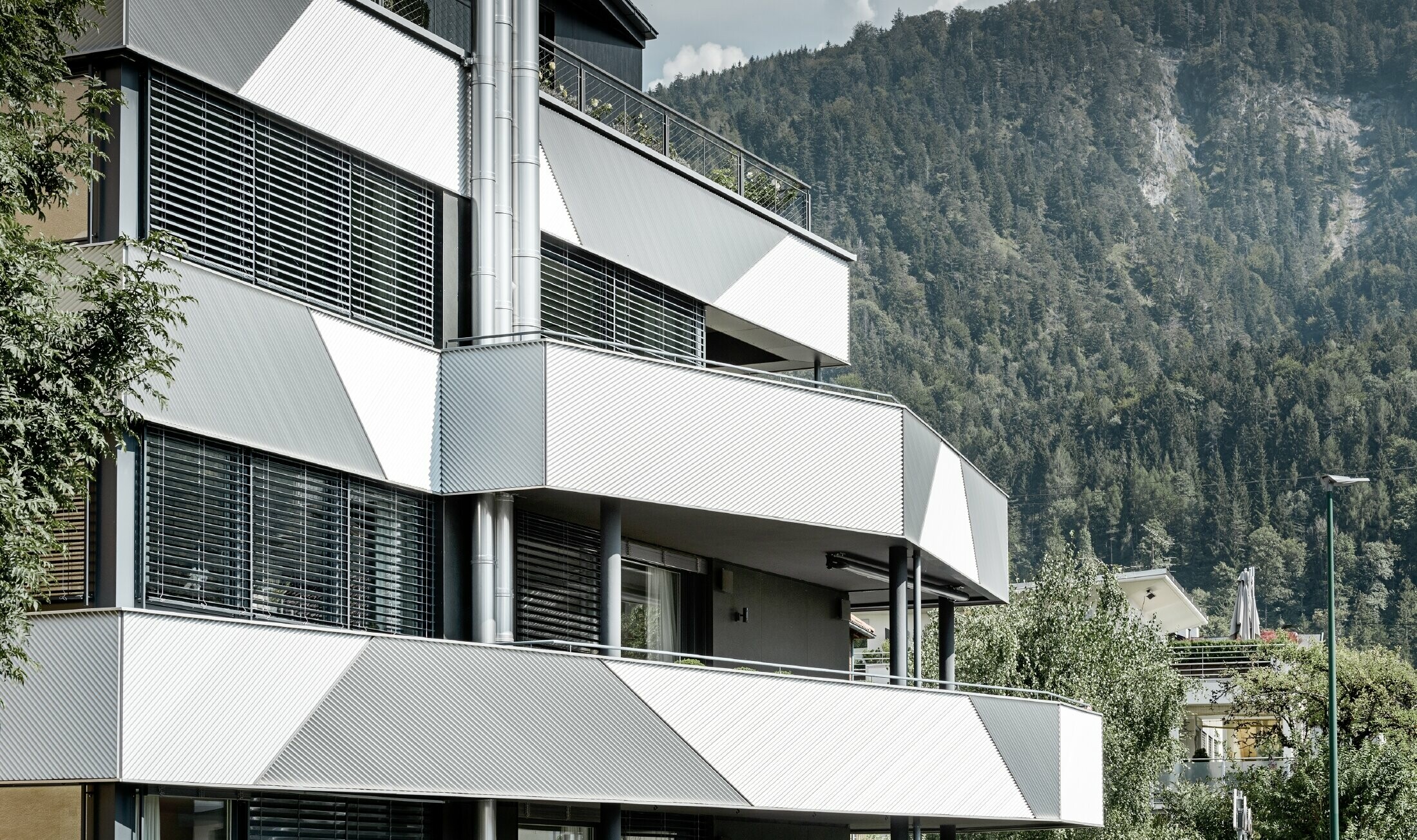 Design della facciata per un condominio con balcone e logge con il profilo a zeta PREFA con posa in diagonale.