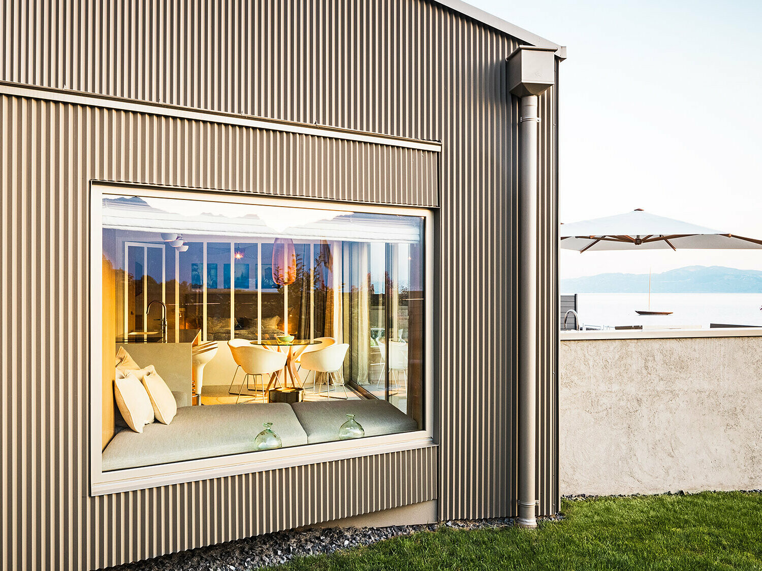 Seitenansicht des Gebäudes mit gezackter Aluminiumfassade, ein Teil des beleuchteten Interieurs ist im Blick.