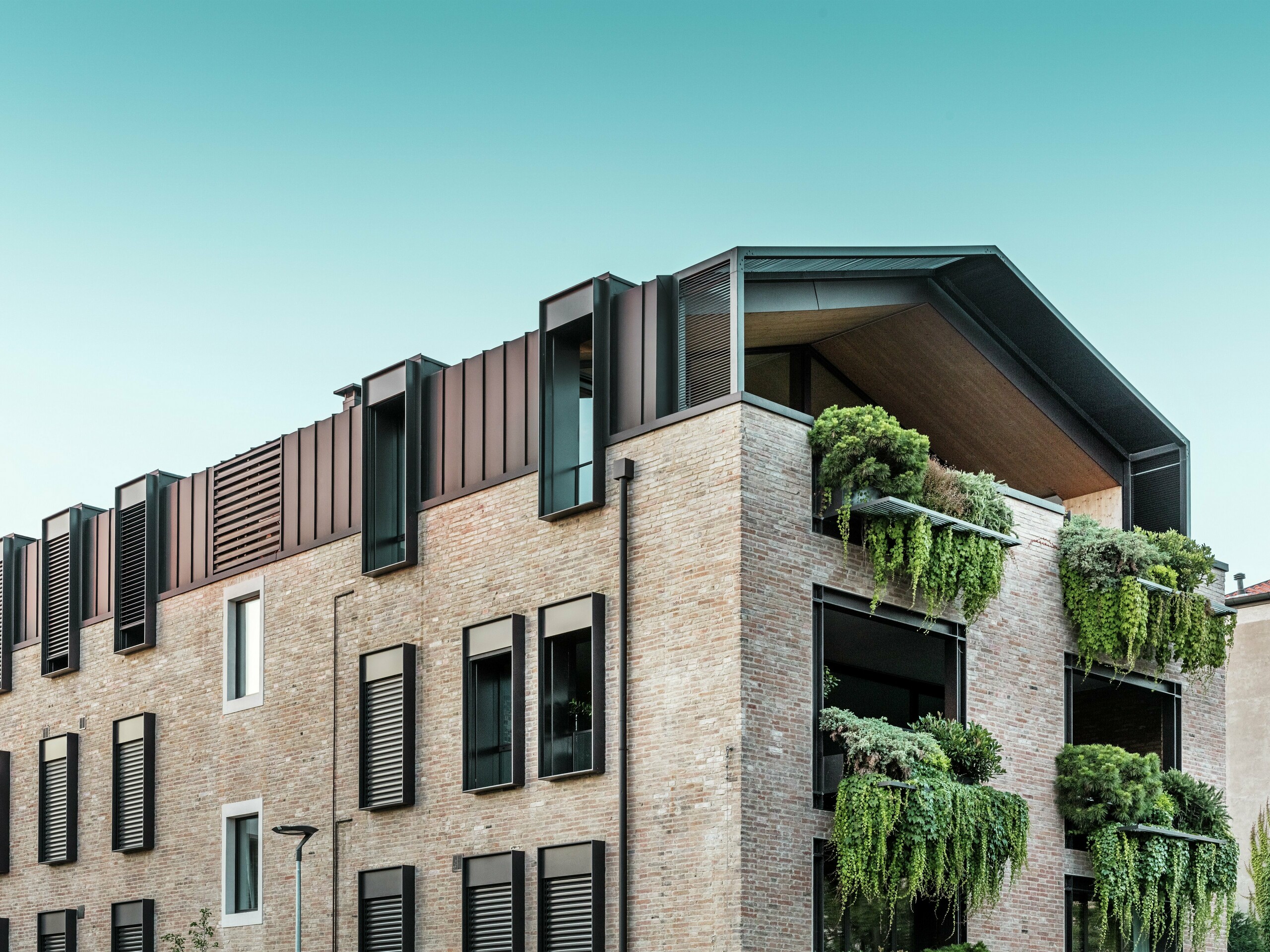Nachhaltiges Wohnhaus in Italien mit PREFALZ Aluminiumdach in P.10 Nussbraun und hängenden Gärten an der Südfassade – klimaaktive Architektur mit Backstein und Begrünung