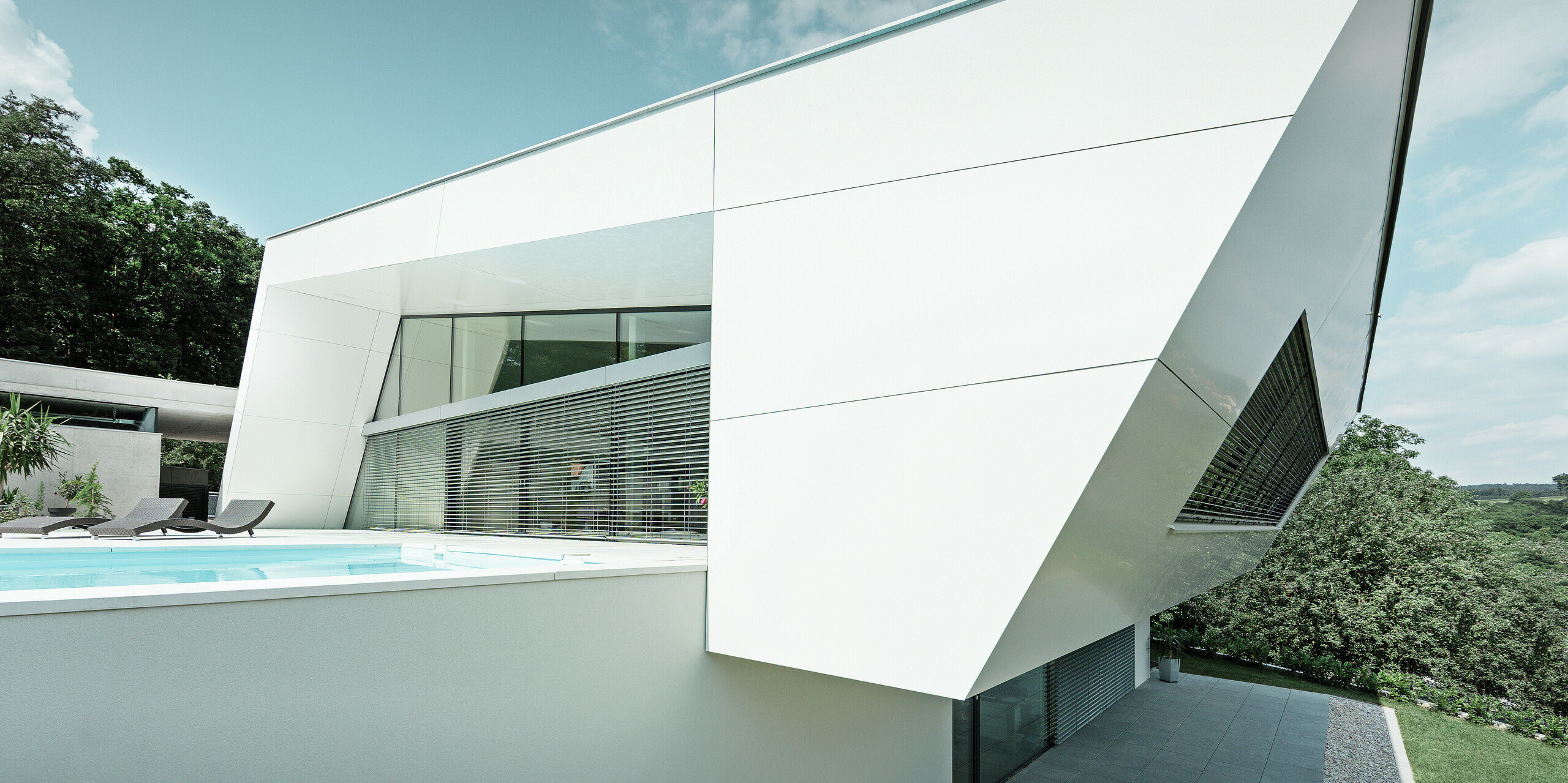 Die schrägen Linien und klaren Kanten des Wohnhauses werden durch die weiße PREFA Aluminiumfassade betont. Die PREFA Aluminium Verbundplatten in P.10 Reinweiß unterstreichen die zeitgemäße Architektur und verleihen dem Gebäude ein unverwechselbares Erscheinungsbild.