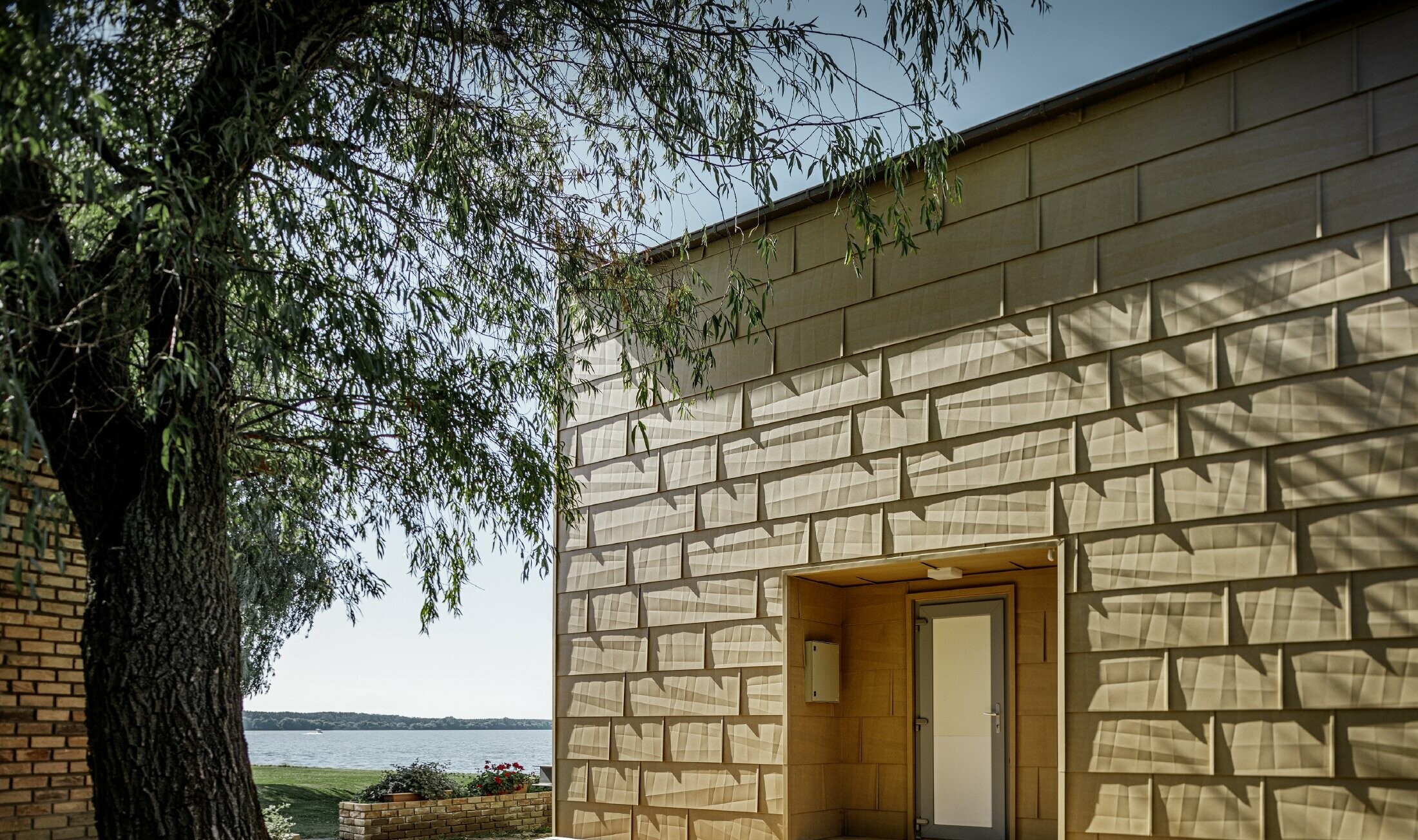 Seconda casa moderna con copertura piana e ampie facciata finestrate al lago con una facciata spigolosa in alluminio in marrone sahara 