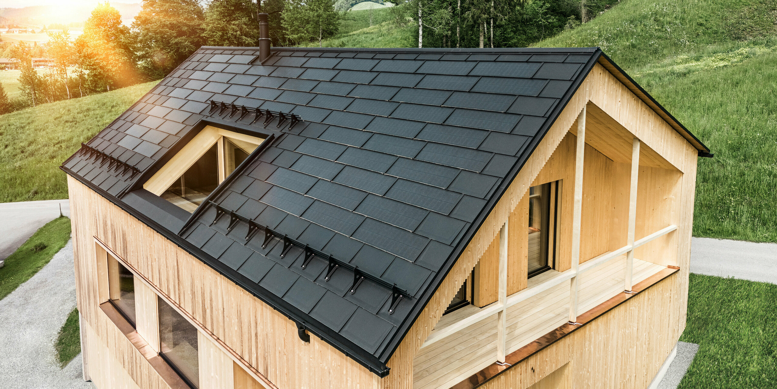 PREFA Solardachplatte und PREFA Dachplatte R.16 in Schwarz verlegt auf einem Einfamilienhaus mit Holzfassade im österreichischen Ort Egg. 