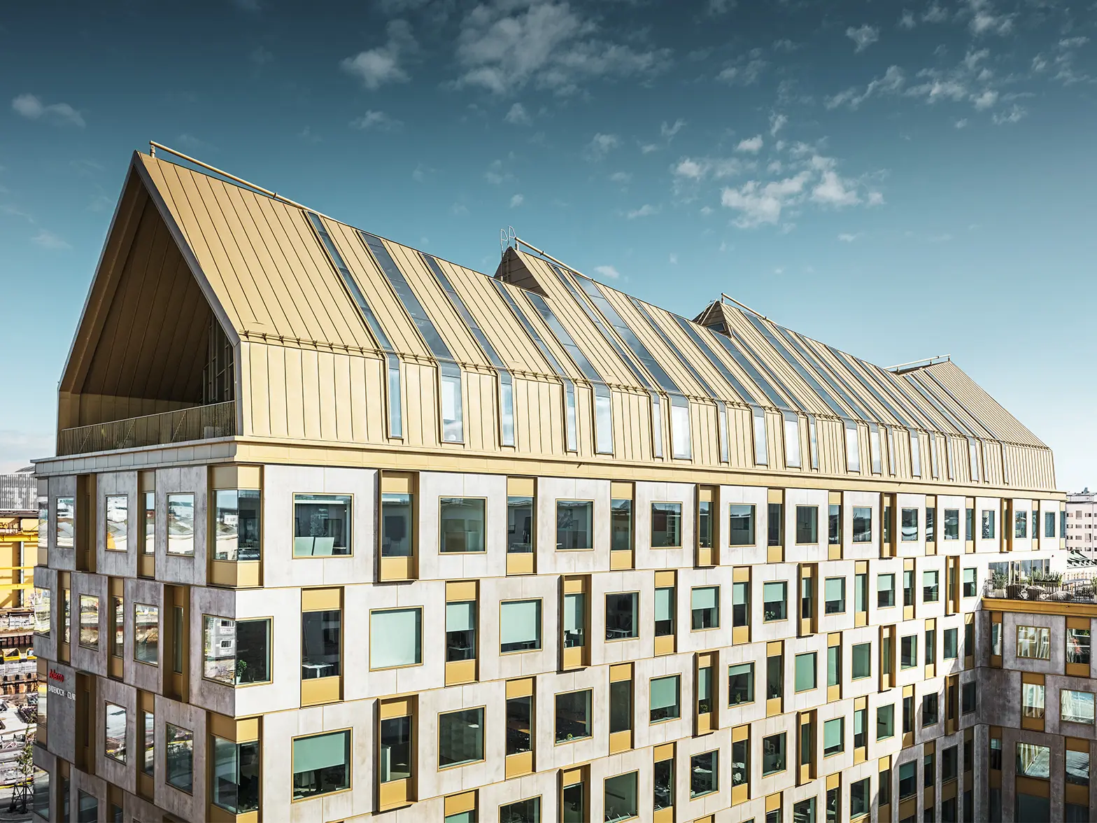 seitliche Frontansicht des Kontorgebäudes in Schweden bei Sonnenschein eingedeckt mit dem Dachsystem PREFALZ in der Sonderfarbe Jaisalmer Gold