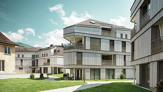 Moderno complesso residenziale a Liebwylen, in Svizzera, con un'architettura chiara e facciate in legno.  I tetti in alluminio PREFALZ di colore marrone sono dotati di lucernari rotondi e completano il design contemporaneo. In primo piano, un'area verde ben curata con sentieri curvilinei e aree di seduta.