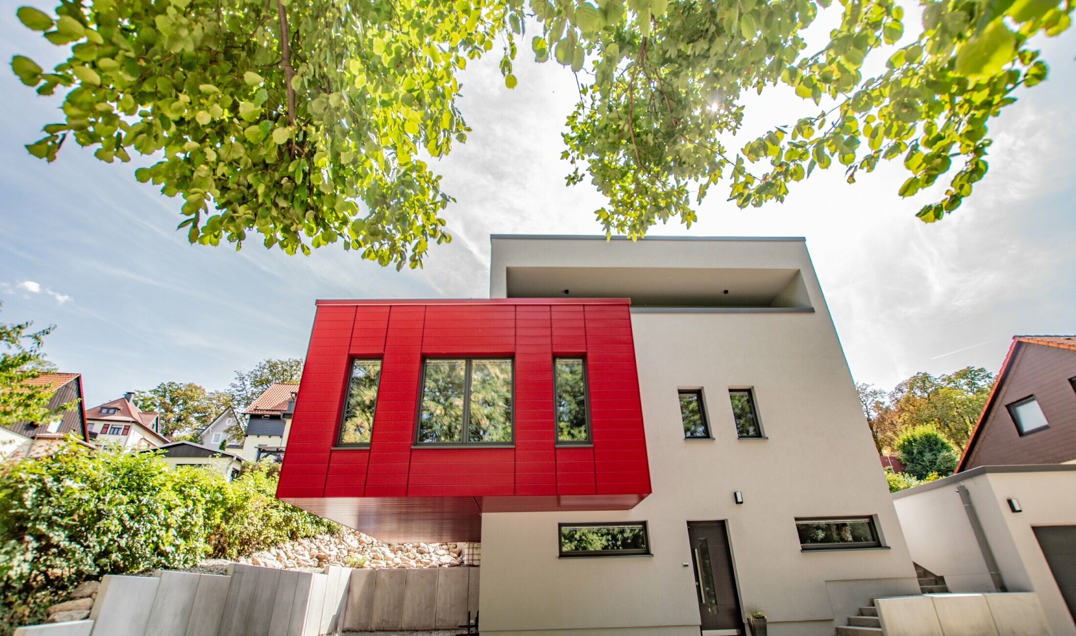 Parte aggettata dell'edificio rivestita con doghe PREFA in rosso rubino. Ampio bovindo di colore rosso che risalta sulla facciata bianca.