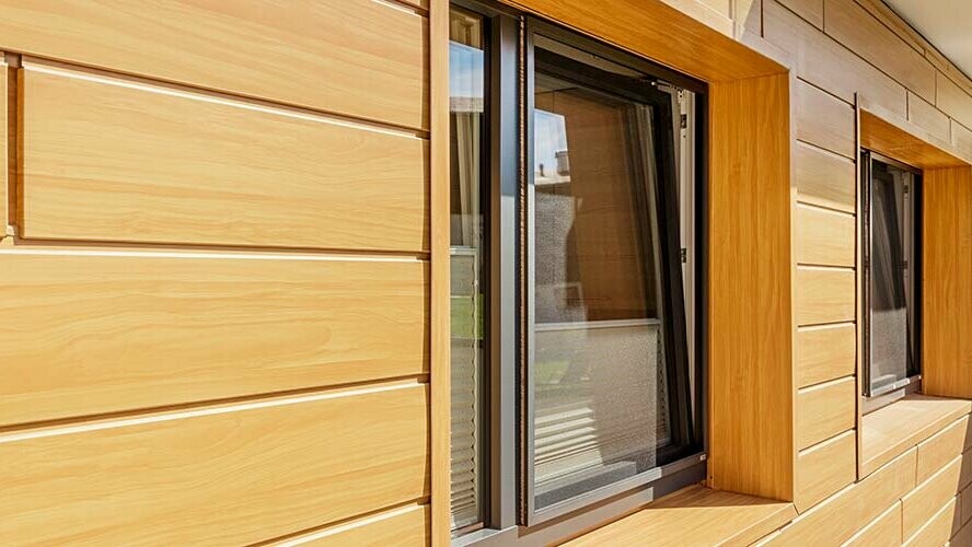 Rivestimento di facciata con pannelli in alluminio con doghe di rivestimento PREFA con effetto rovere naturale; imbotte finestra resistente alle intemperie in rovere naturale.
