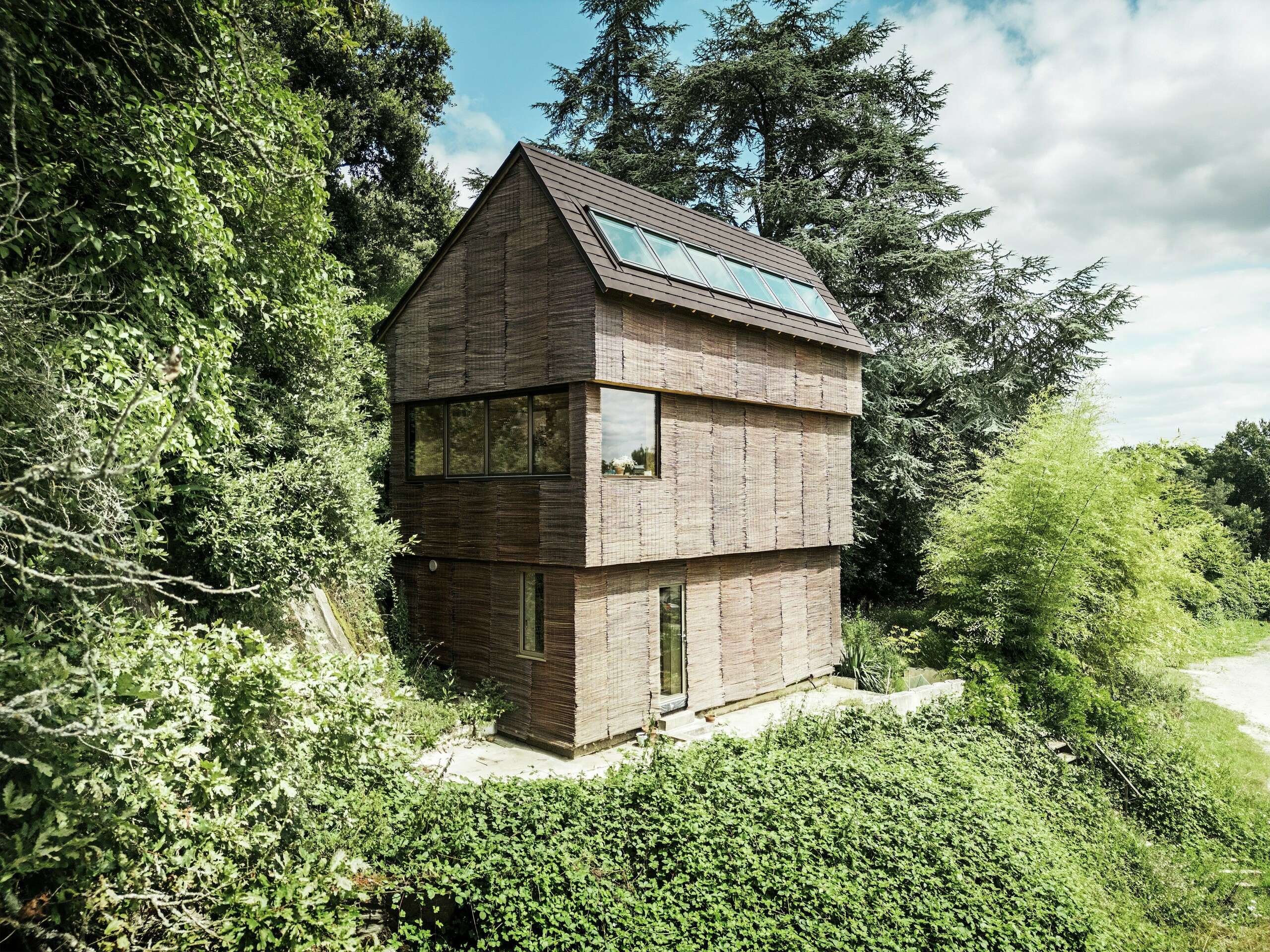Casa in Francia con scandole PREFA in P.10 testa di moro e facciata in salice, immersa nel verde - architettura sostenibile e design ecologico.