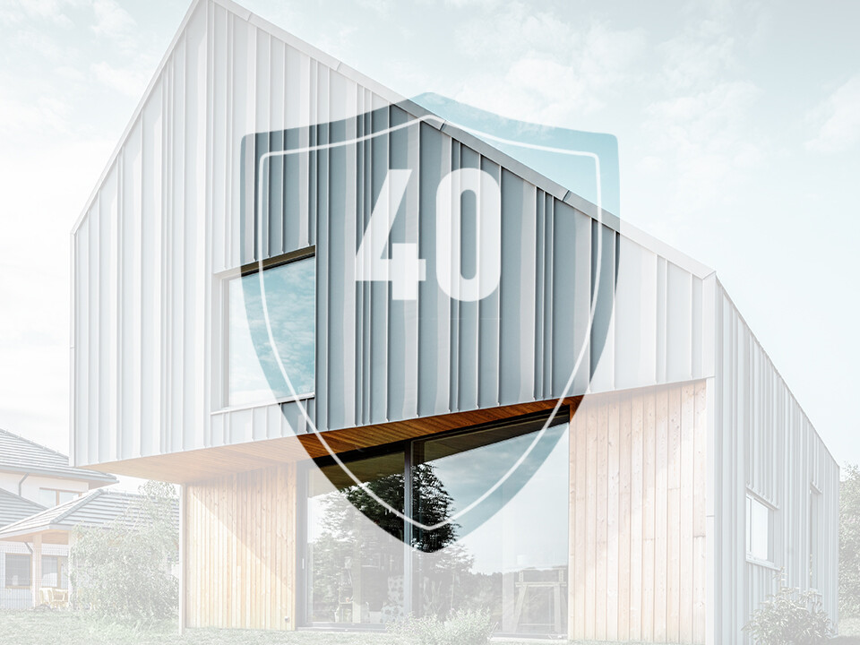 L'immagine mostra un cartello con il numero “40”, che rappresenta la garanzia sui prodotti in alluminio PREFA, davanti a una moderna casa unifamiliare.