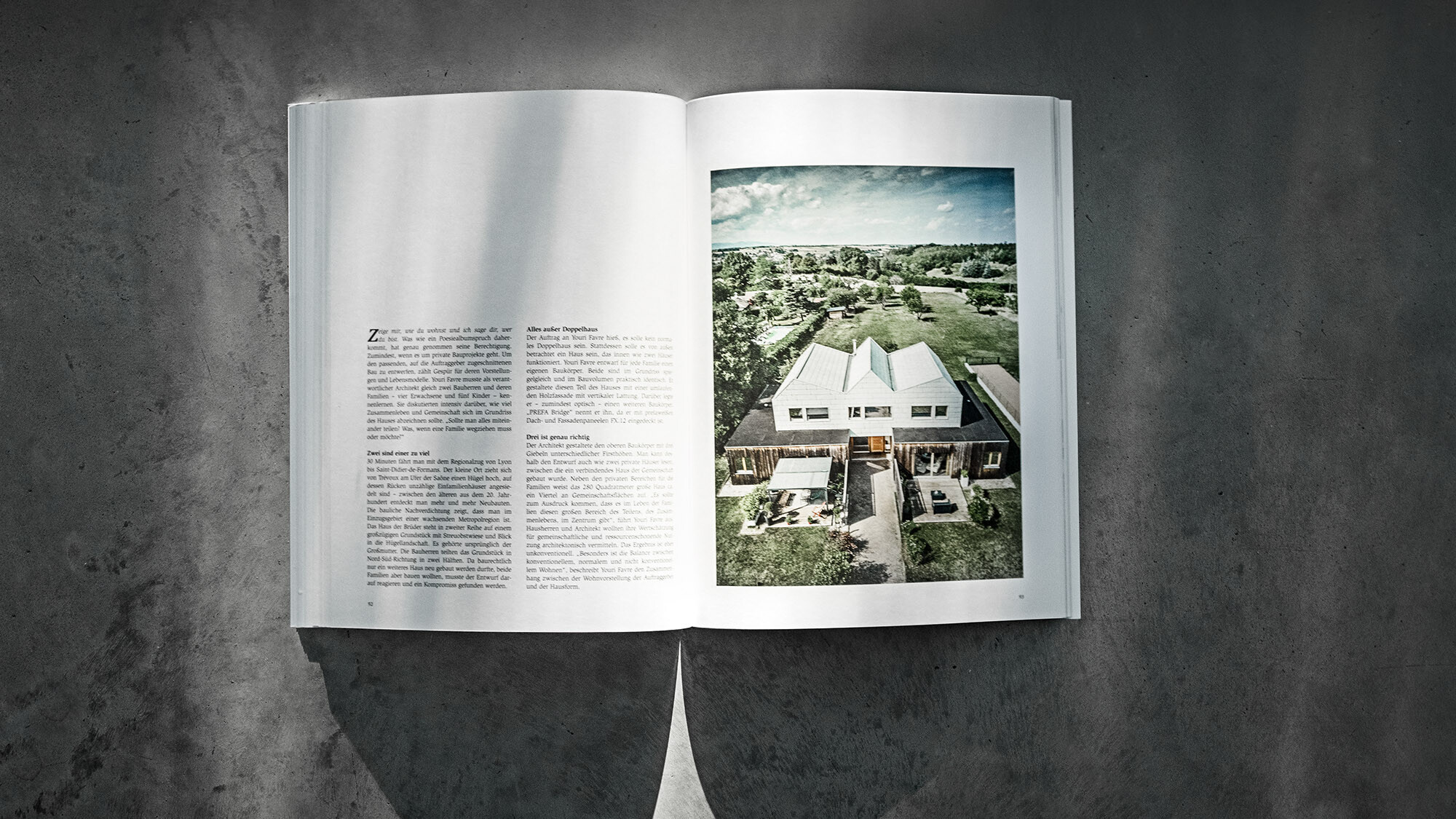Libro PREFARENZEN 2024 aperto, su sfondo grigio, con un articolo sulla casa bifamiliare di Youri Favre Architecture.