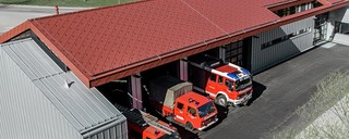 Feuerwehrautos im Feuerwehrhaus der Betriebsfeuerwehr der Firma PREFA. Das Gebäude hat ein rotes Rautendach aus nicht brennbarem Aluminium und eine Alufassade.