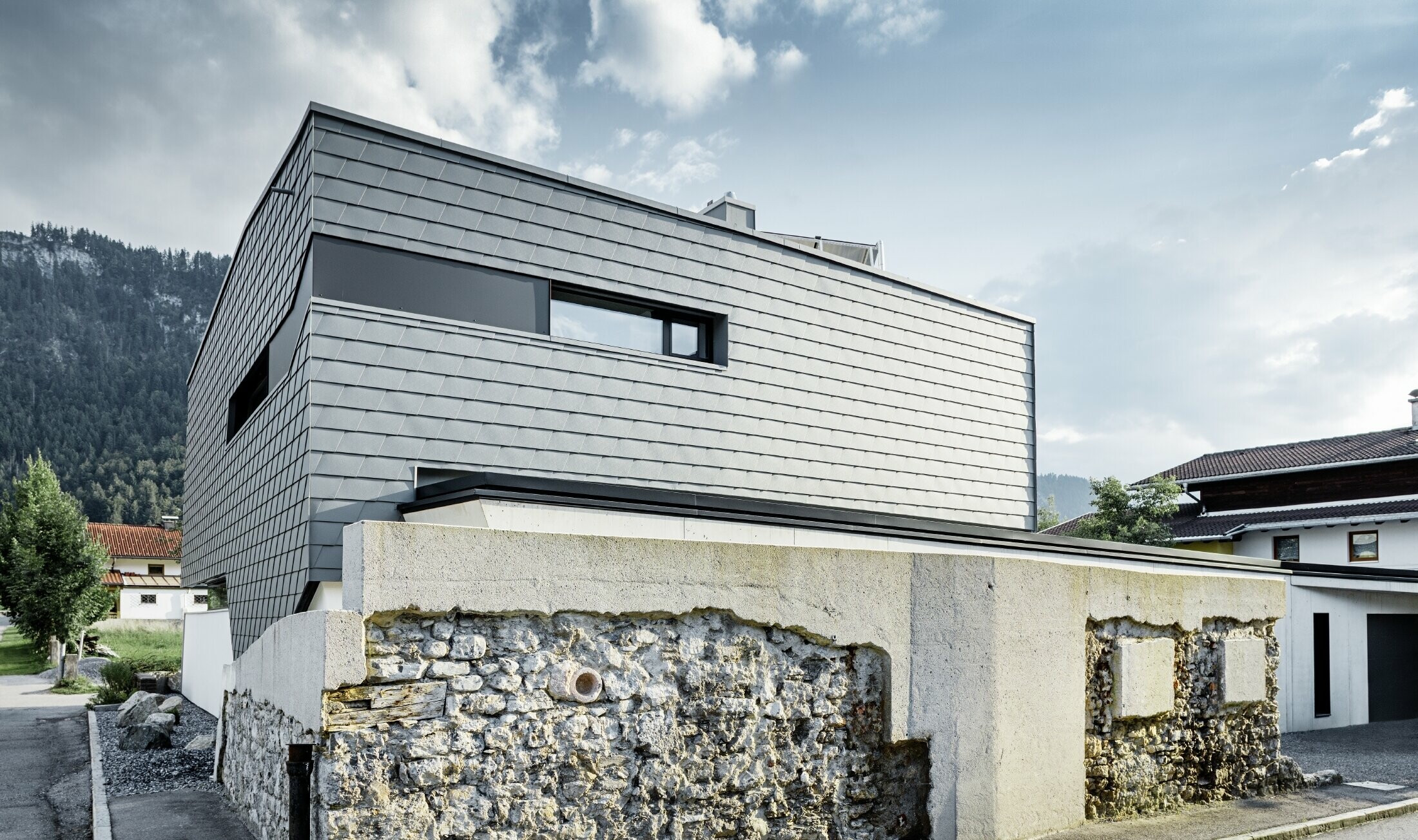 casa unifamiliare moderna con copertura piana, ampie superfici vetrate e una facciata in scandola in grigio chiaro in alluminio PREFA