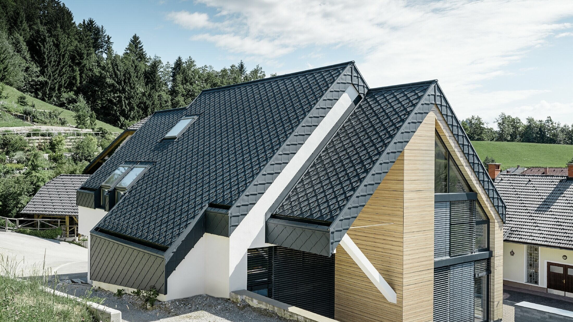 Casa unifamiliare con tetto a due falde senza cornicione, con una facciata effetto legno ed un tetto in alluminio in antracite
