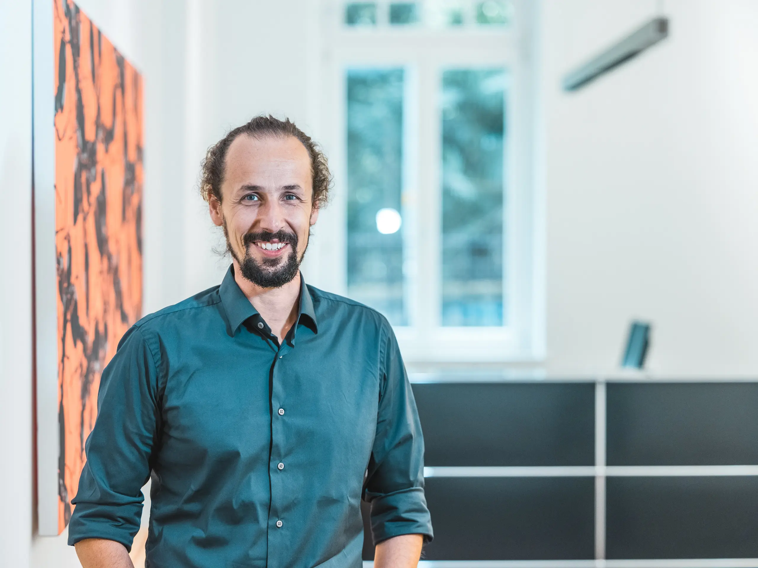 Ritratto dell’architetto Gianfranco Berardesca in un ambiente interno moderno. Il responsabile di progetto dello studio Höller & Klotzner Architekten ha seguito la realizzazione del centro di formazione di Riffian in Alto Adige. L’edificio, premiato con il riconoscimento PREFARENZEN, è stato realizzato con scaglie PREFA di dimensioni 44 × 44 e colore P.10 bronzo ed è sinonimo di progettazione accurata, qualità architettonica e artigianato altoatesino.