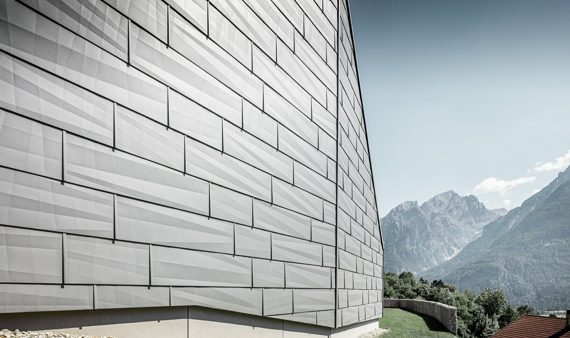 Il lato esposto alle intemperie della casa unifamiliare a Lienz, Austria, è stato rivestito con il pannelli per facciata FX.12 PREFA in P.10 grigio chiaro.
