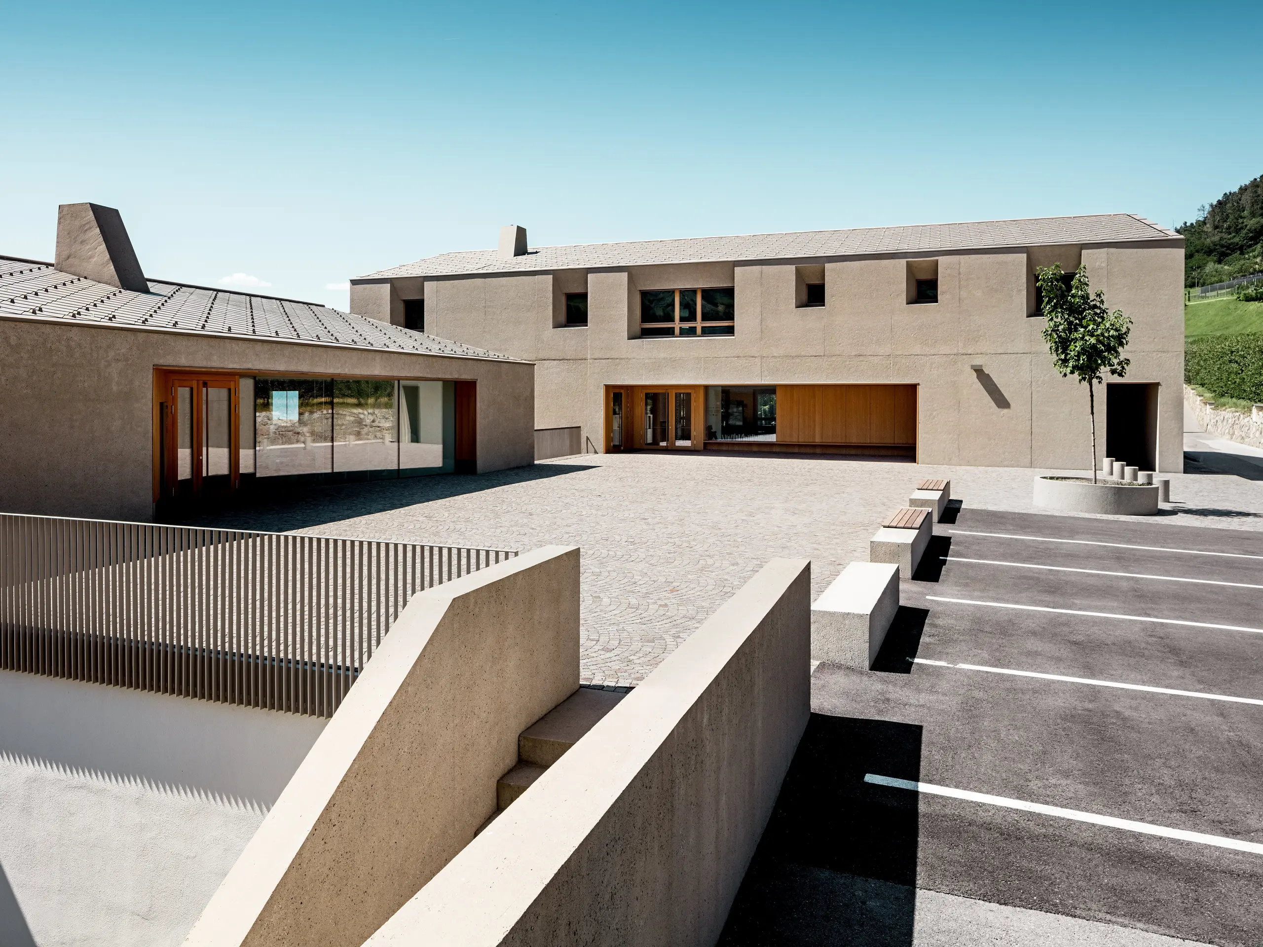 Il centro di formazione di Riffian, in Alto Adige, coniuga un’architettura moderna con un design accurato della copertura. I due corpi edilizi, con scaglie 44 × 44 PREFA nella finitura P.10 bronze, si integrano armoniosamente nel paesaggio. La copertura in alluminio, di lunga durata, garantisce una protezione affidabile dagli agenti atmosferici e sottolinea il linguaggio formale pulito dell’edificio scolastico.