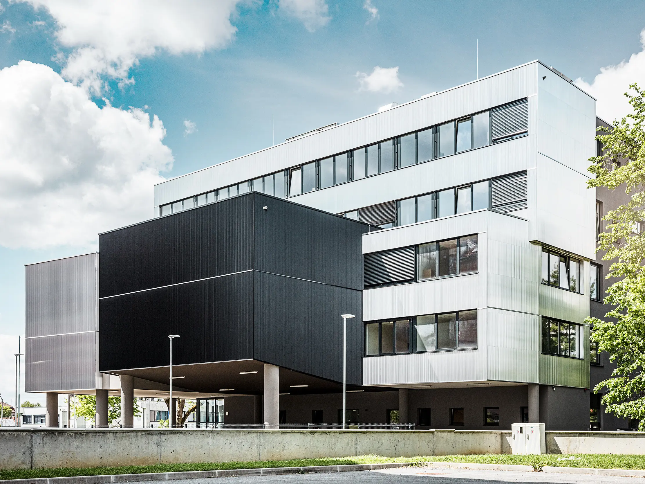 Vista laterale della scuola di musica di Bjevolar con una moderna facciata PREFA con Profilo a zeta. La facciata è realizzata nelle tonalità nero e alluminio naturale, e le forme geometriche conferiscono un design essenziale e di forte carattere.