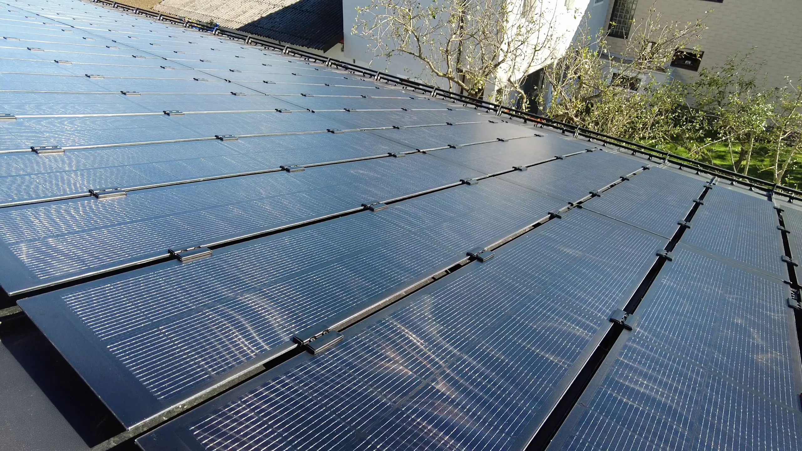 Vista di un tetto dotato di moduli fotovoltaici PREFALZ, con moduli fotovoltaici vetro/vetro adattati con precisione alle larghezze delle lastre in doppia aggraffatura.