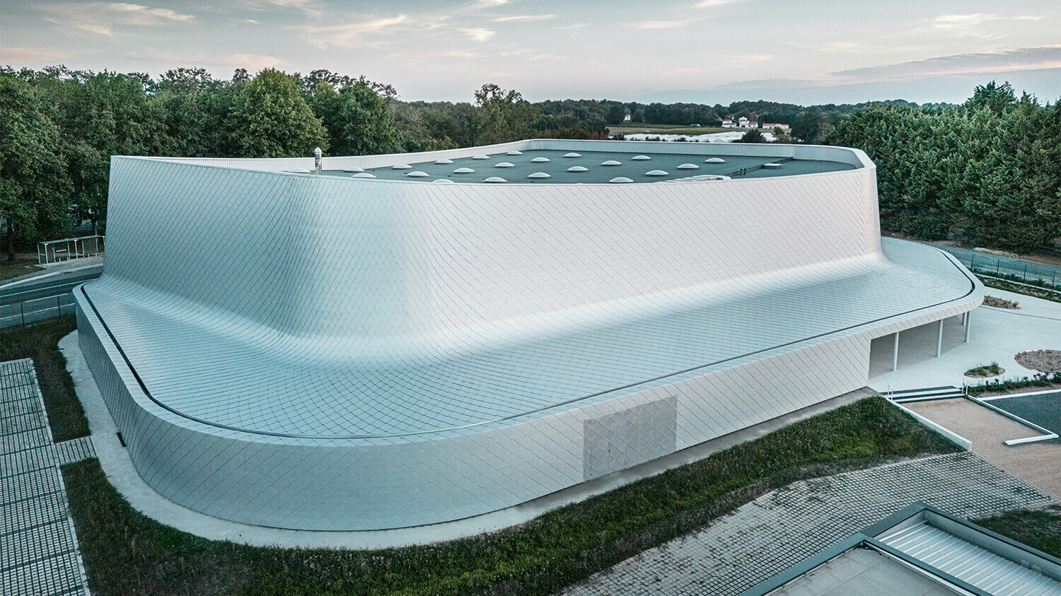 Prospettiva dall'alto su un lato dell'edificio con la natura circostante e con vista sulla superficie del tetto.