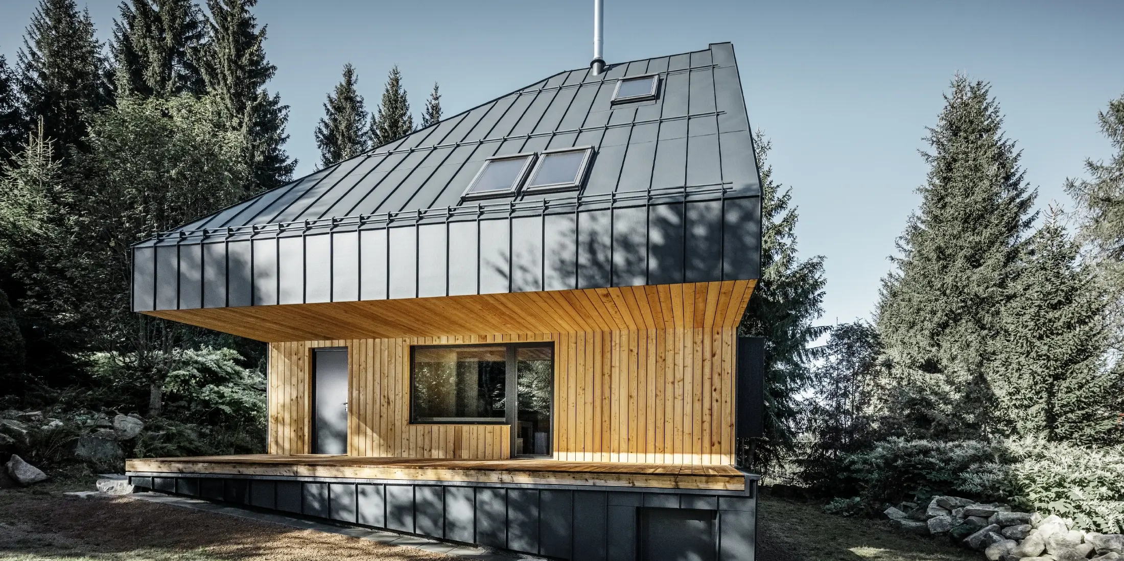 Architektonisches Einfamilienhaus im Wald, das imposante Dach wurde mit Prefalz Aluminium von PREFA in Anthrazit verkleidet. Die Untersicht sowie die Fassade ist mit Holzpaneelen verkleidet.