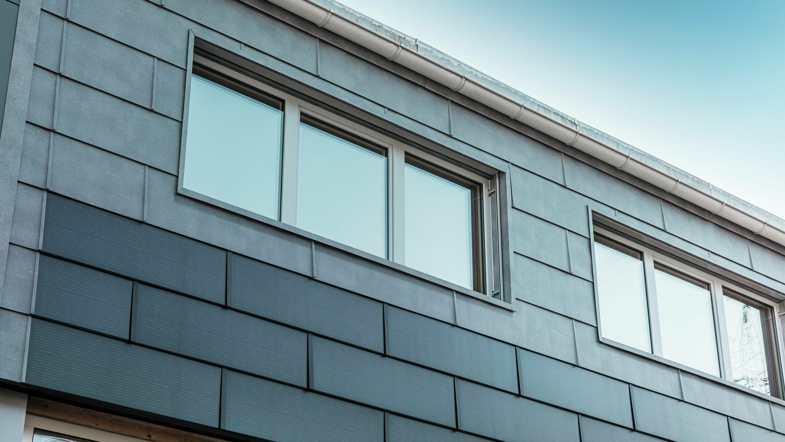 La facciata dell'edificio aziendale è stata rivestita con innovative tegole fotovoltaiche, combinate con i pannelli per facciata FX.12 di PREFA.