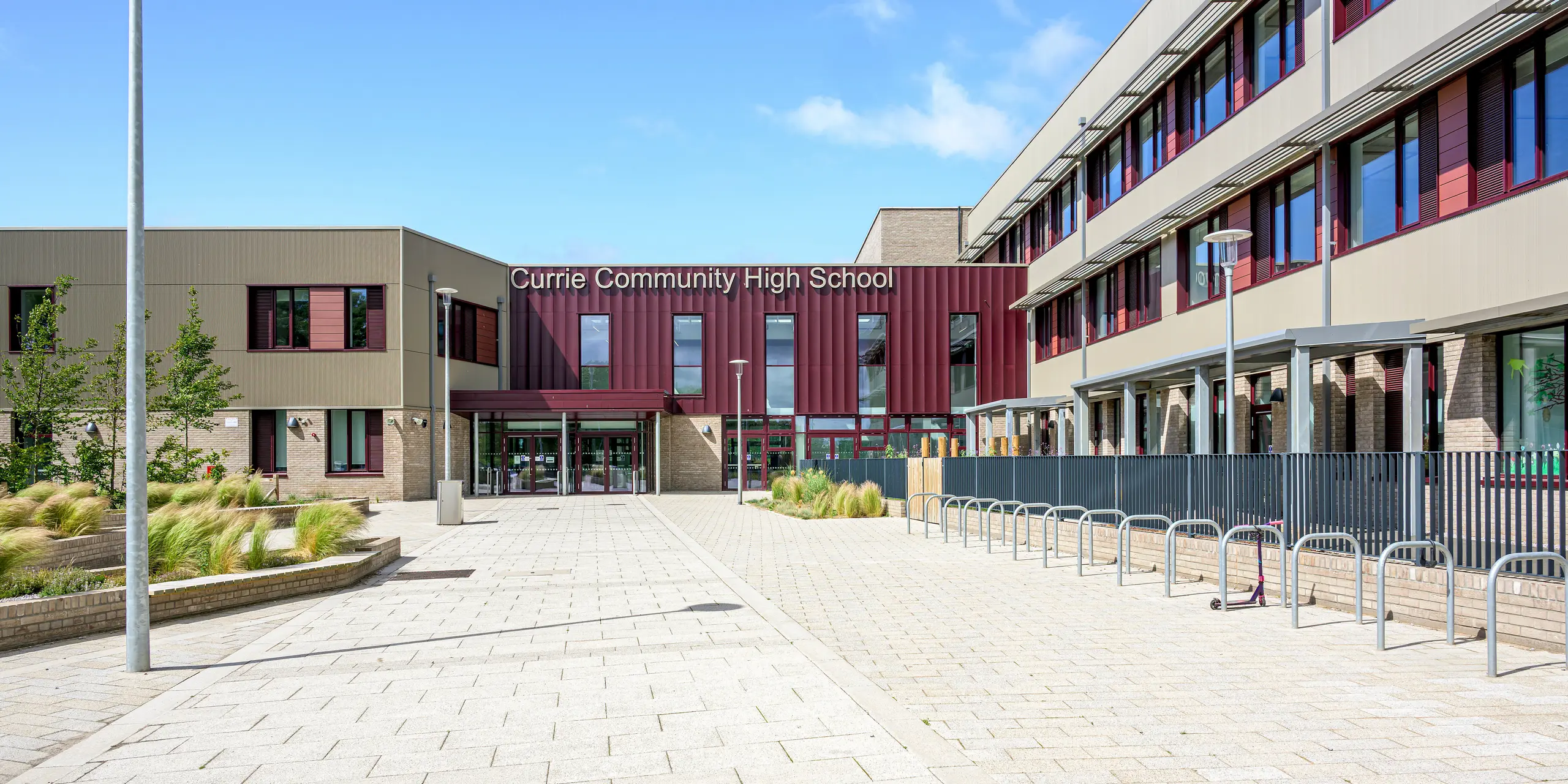Die großzügige Eingangszone der Currie Community High School in Edinburgh wird von der markanten PREFA Fassade mit Strangpressprofil Zacke geprägt. Die vertikale Aluminiumstruktur in P.10 Prefabronze setzt rund um den Haupteingang spannende Akzente und verleiht dem Schulgebäude eine moderne, hochwertige Ausstrahlung. Das langlebige, korrosionsbeständige und wartungsarme PREFA Aluminiumsystem verbindet architektonische Eleganz mit nachhaltiger Beständigkeit.