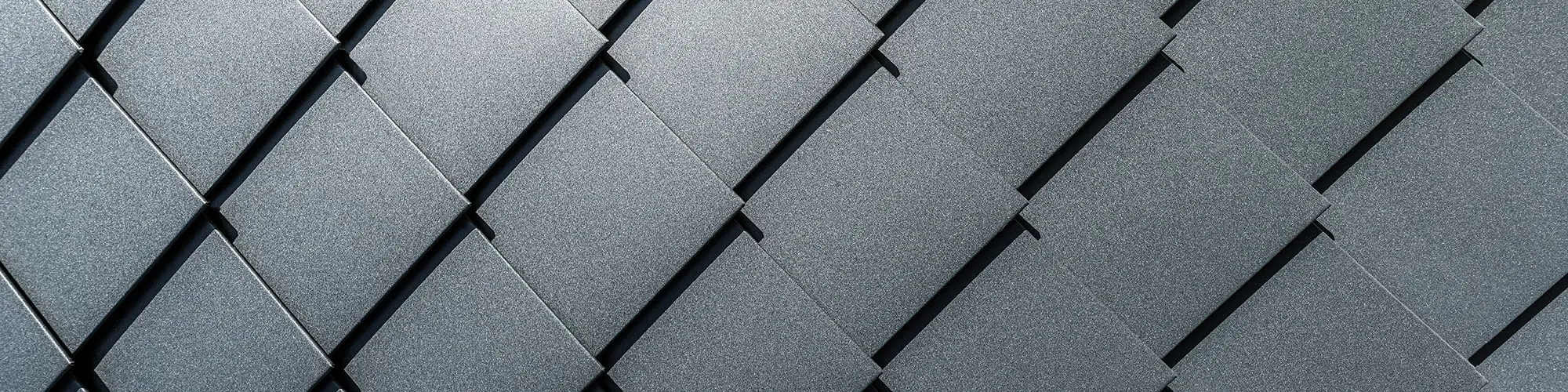Eine Detailaufnahme der Fassade mit den haargenau verlegten, anthrazitfarbenen Wandrauten.