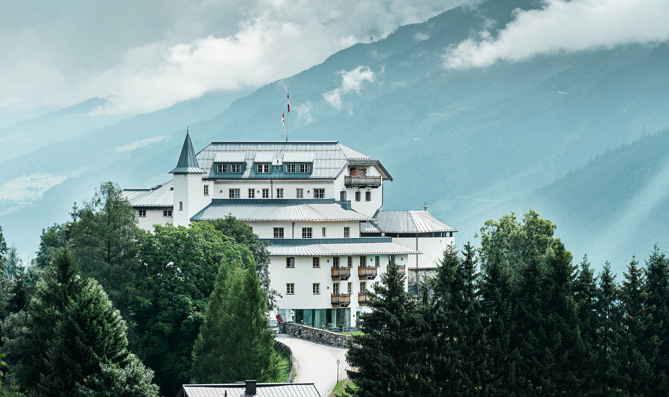 Castello Mittersill circondado da alberi e montagne con una copertura in Prefalz in grigio pietra ristrutturato