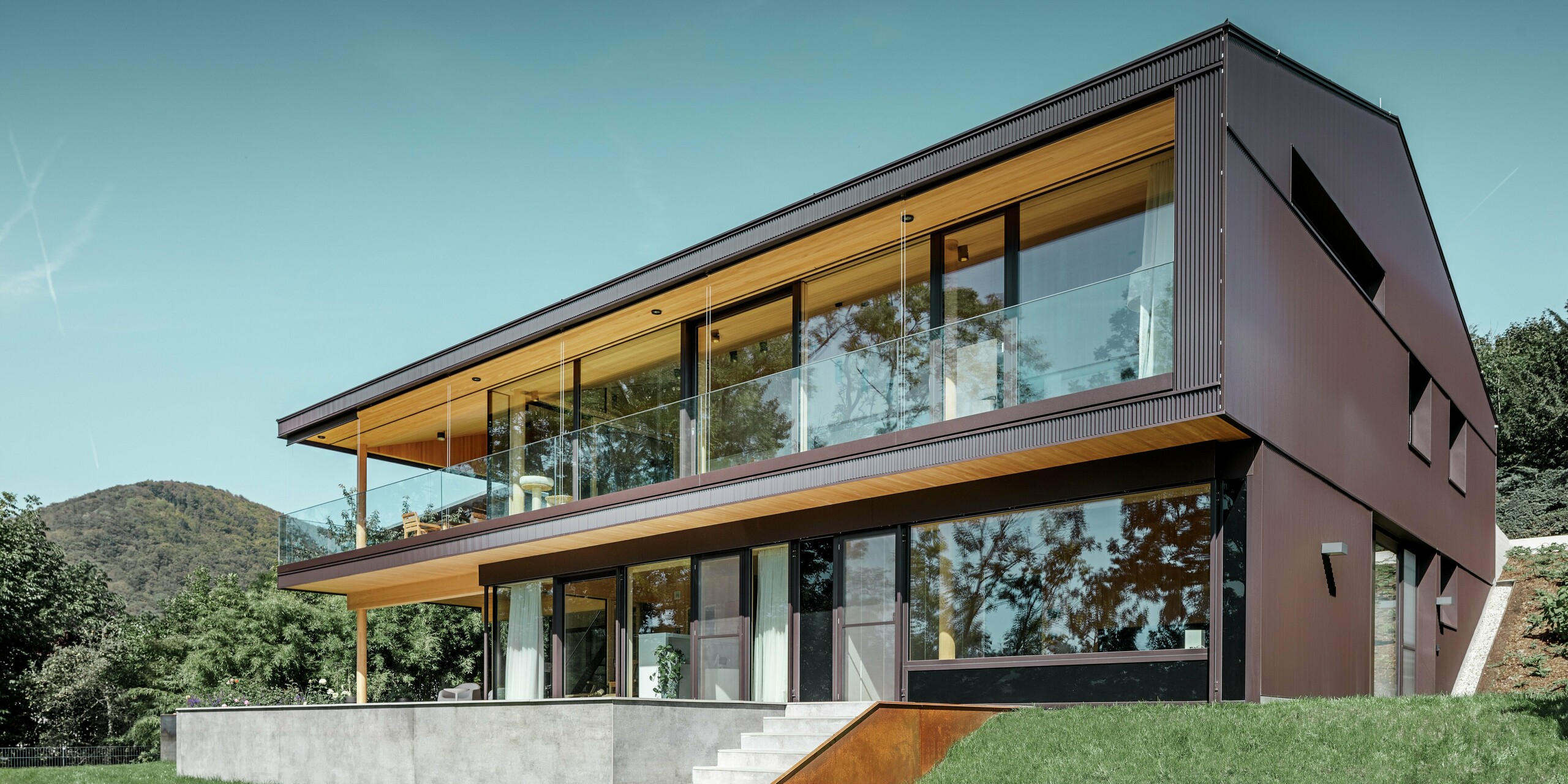 Moderna casa unifamiliare con ampie finestre lato giardino, la facciata è stata rivestita con il profilo a zeta PREFA in marrone scuro.