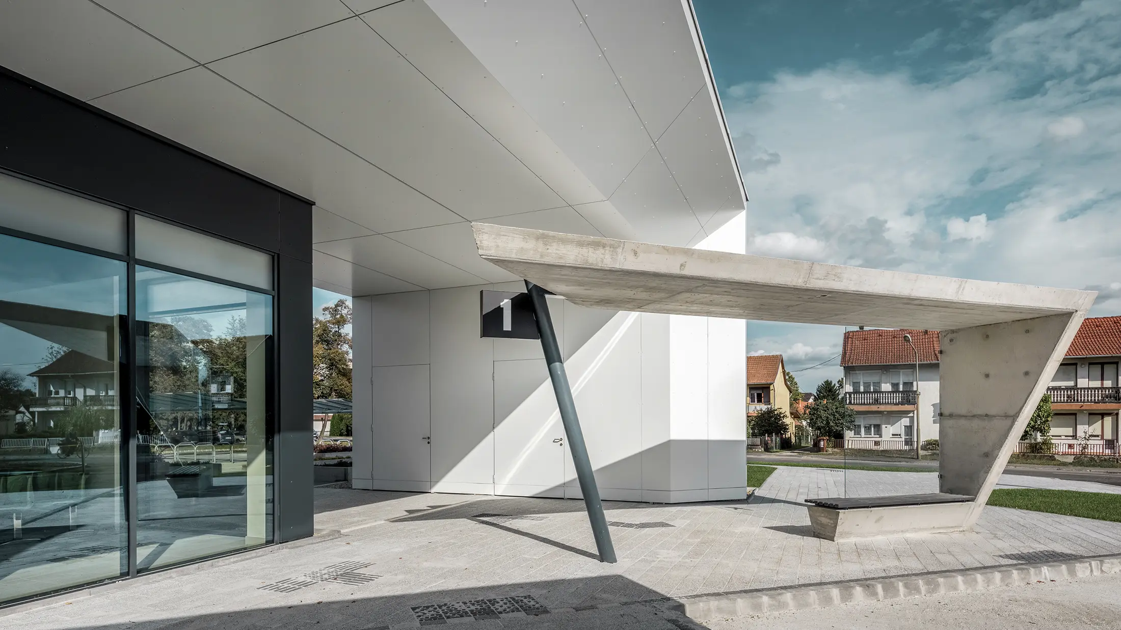 Ingresso della stazione degli autobus di Lenti; la parte inferiore della copertura è rivestita con pannelli compositi in alluminio PREFABOND di PREFA in bianco puro, mentre gli elementi della facciata in corrispondenza delle porte d'ingresso e delle vetrine sono rivestiti in P.10 antracite.