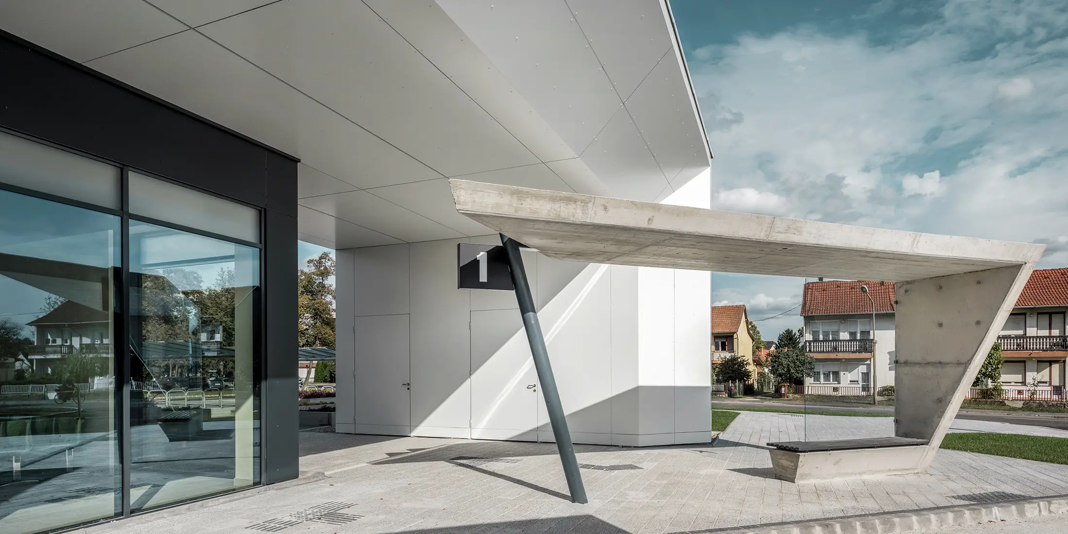 Ingresso della stazione degli autobus di Lenti; la parte inferiore della copertura è rivestita con pannelli compositi in alluminio PREFABOND di PREFA in bianco puro, mentre gli elementi della facciata in corrispondenza delle porte d'ingresso e delle vetrine sono rivestiti in P.10 antracite.