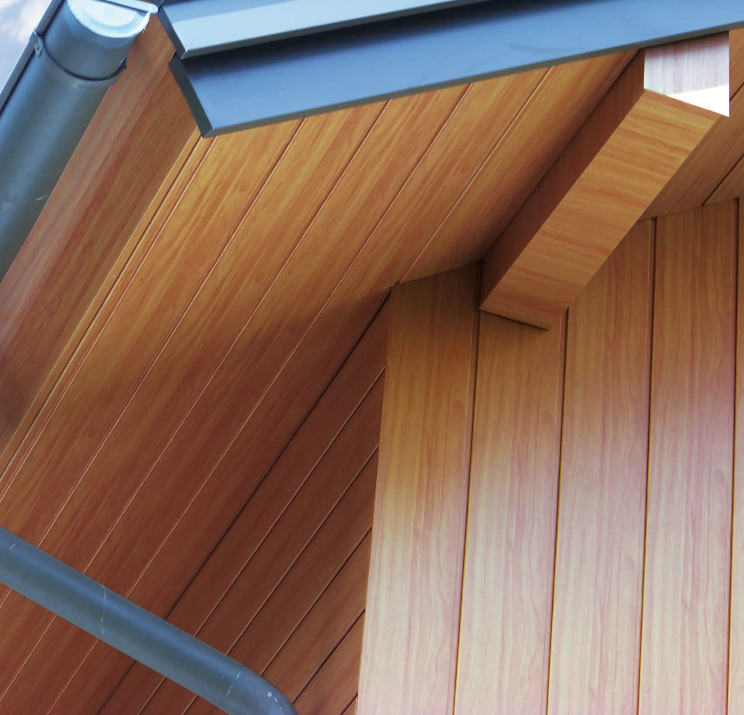 Intradosso del tetto rivestito con doghe di rivestimento PREFA di colore legno chiaro in alluminio.
