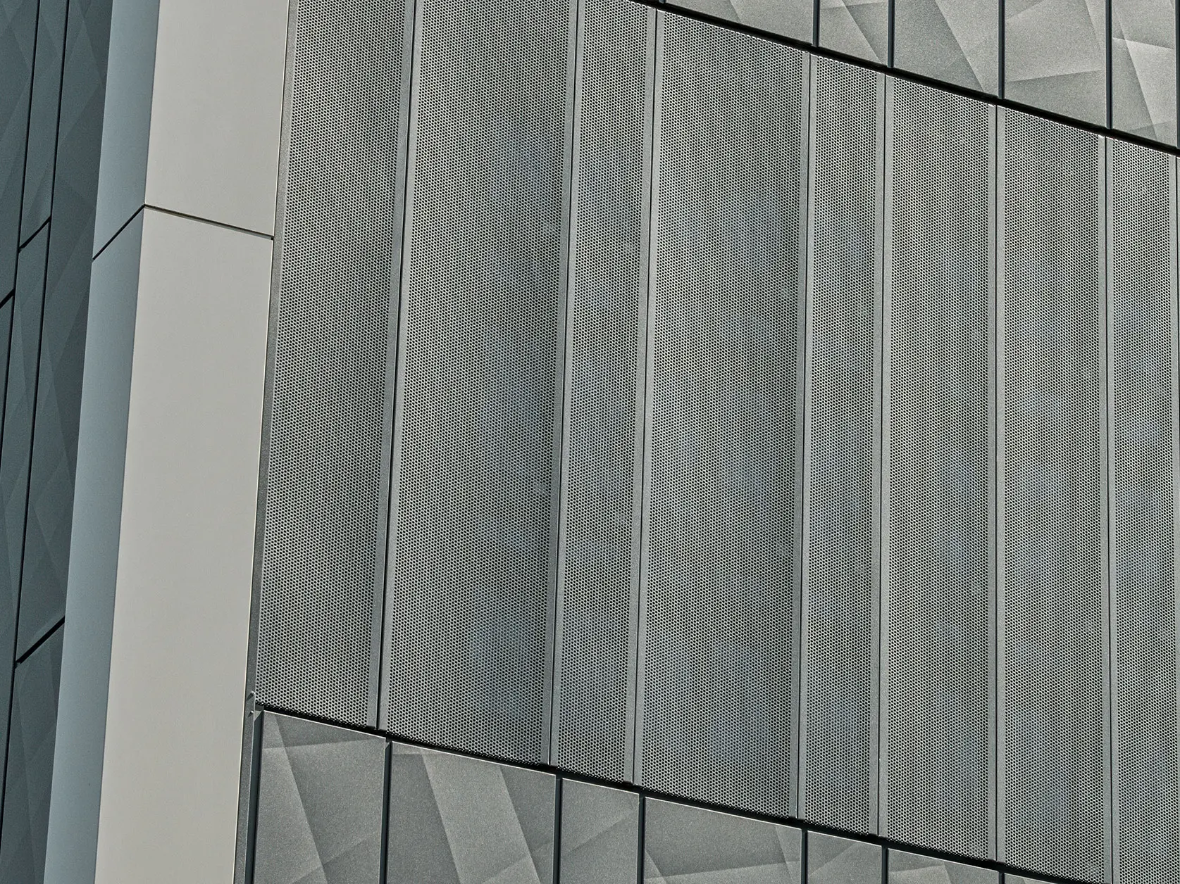 Vista della facciata di un negozio Eurospar a Rohrbach con rivestimento PREFA Siding.X e doghe perforate nel colore antracite. Gli elementi doga.X presentano un vivace disegno geometrico delle fughe, mentre le doghe perforate offrono una struttura moderna e traspirante.