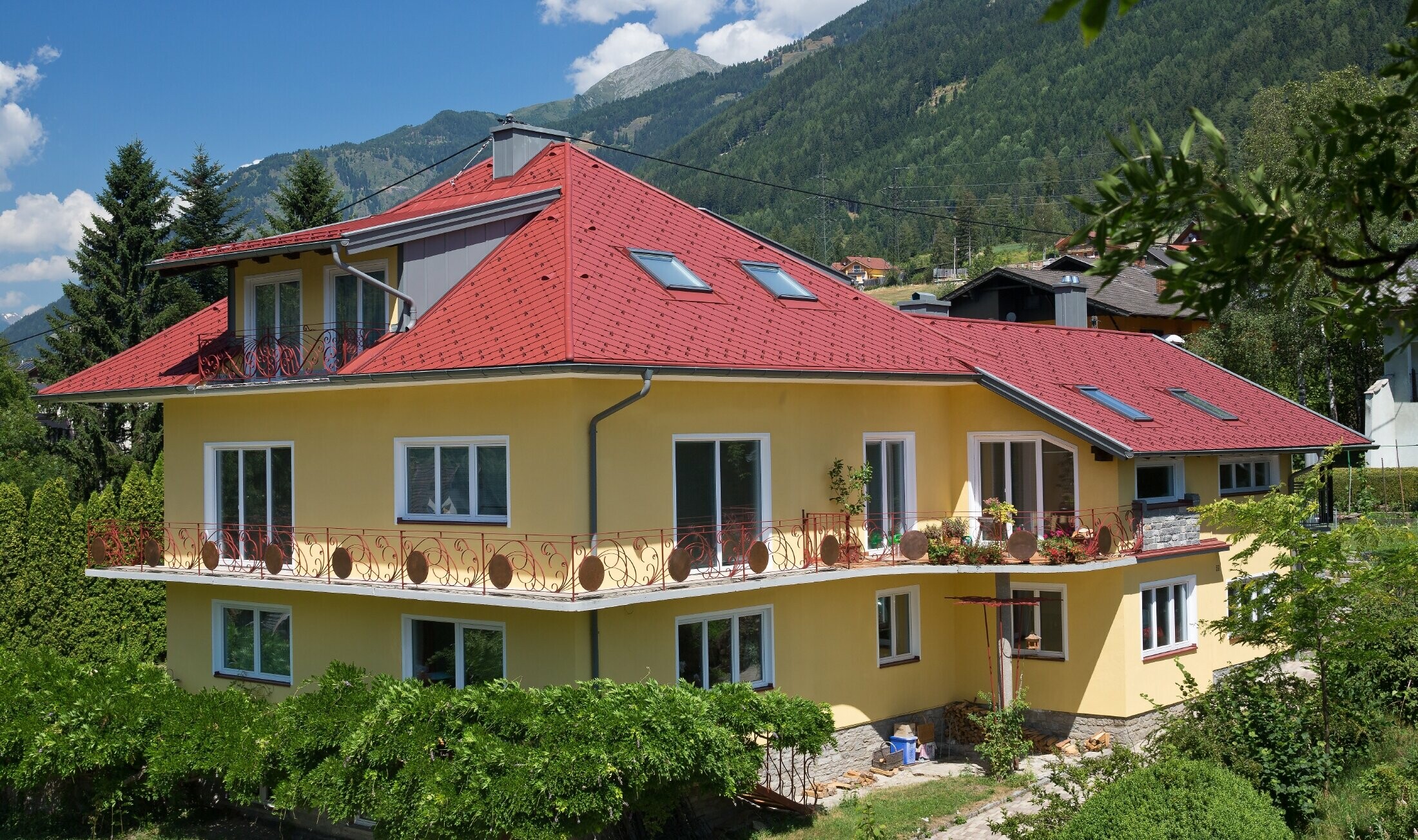 Classica casa unifamiliare con tetto a padiglione, rivestita con le scaglie in rosso ossido.