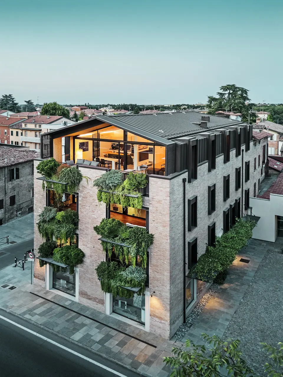 Nachhaltiges Wohnhaus in Italien mit PREFALZ Aluminiumdach und begrünter Backsteinfassade.