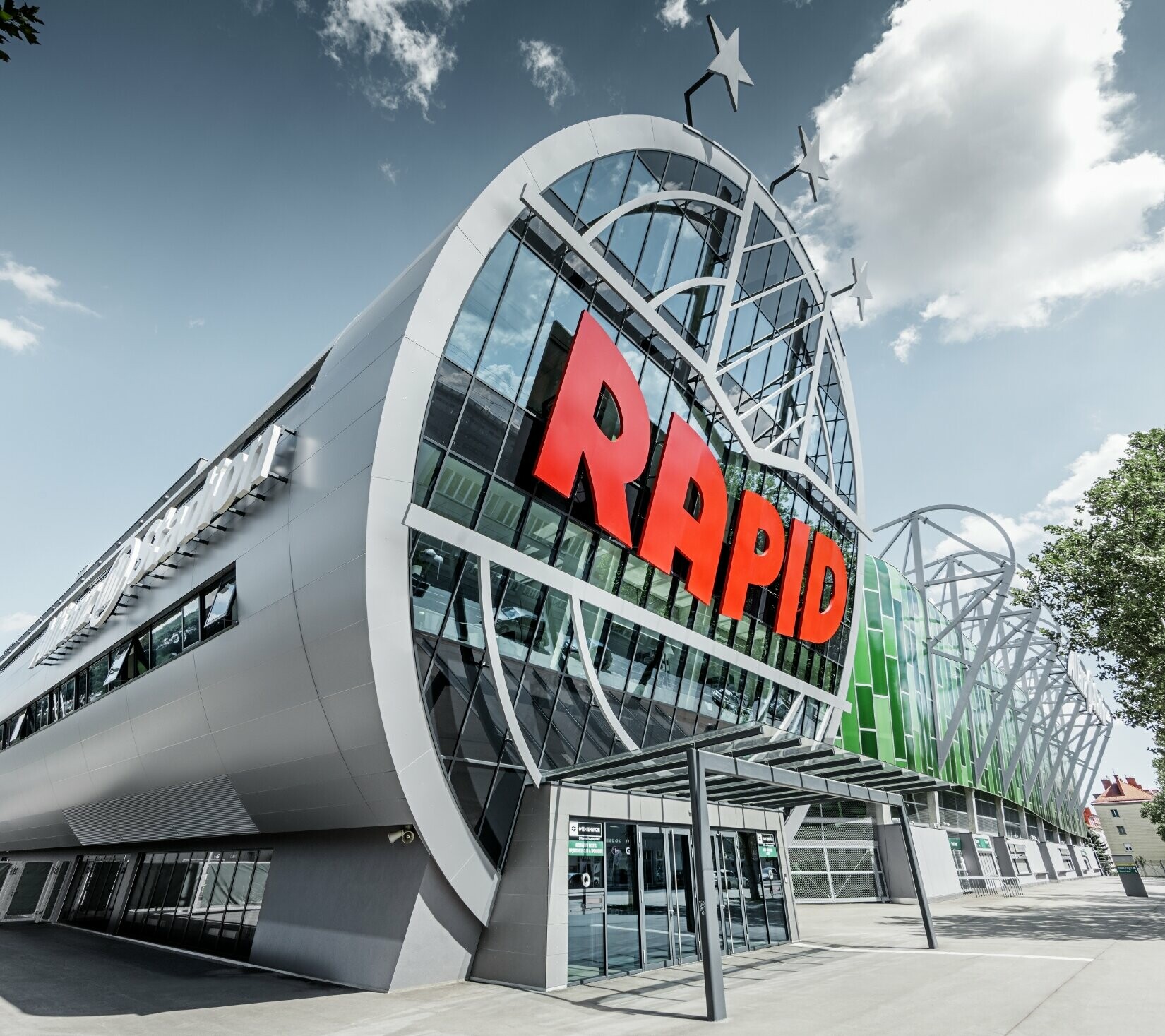 Ingresso all'Allianz Stadion con il grande logo SK Rapid Wien; il tubo con l’ampio frontale in vetro è rivestito con il pannello composito in alluminio PREFA in silver metallizzato.